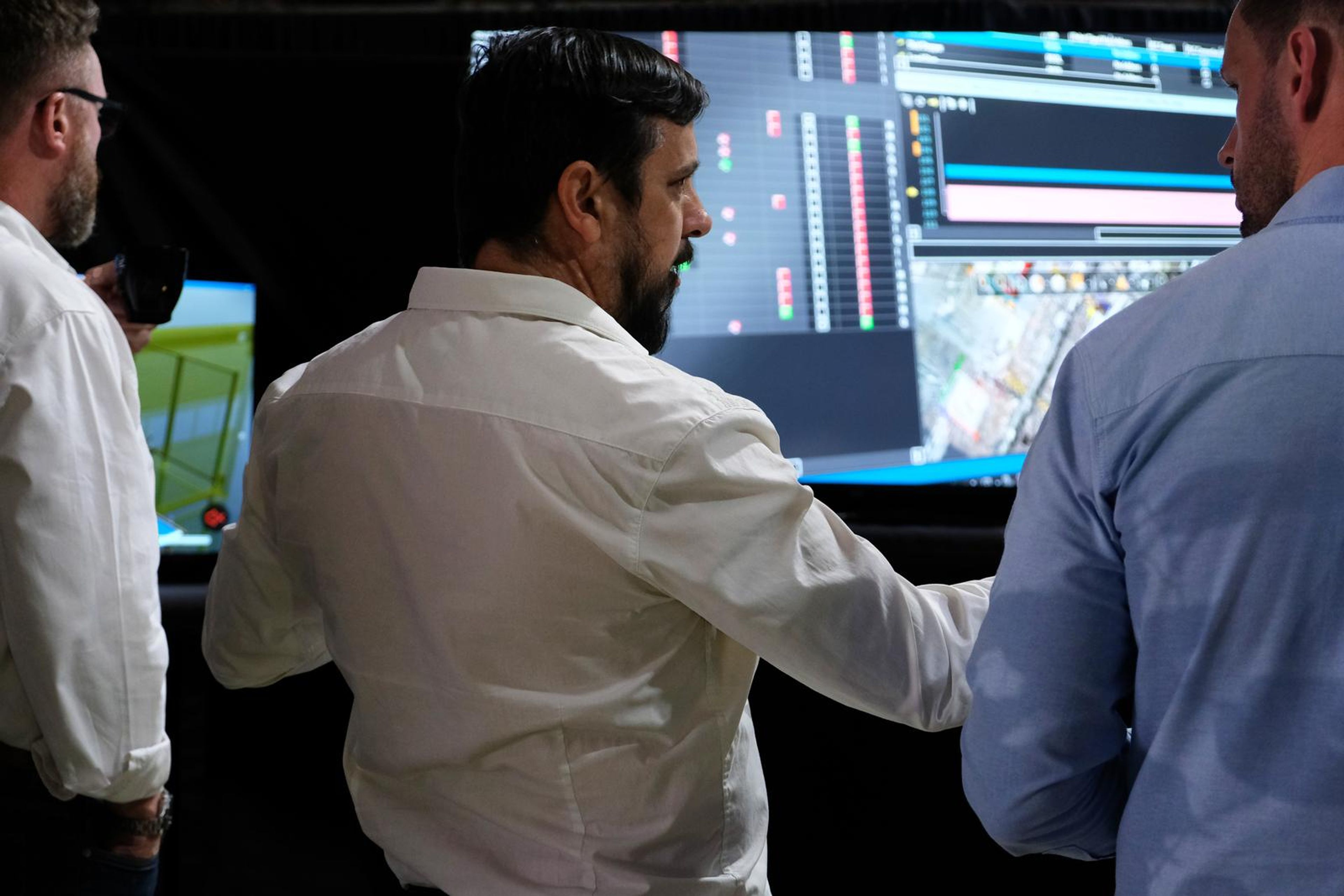 Presenter pointing at a screen showing a production layout