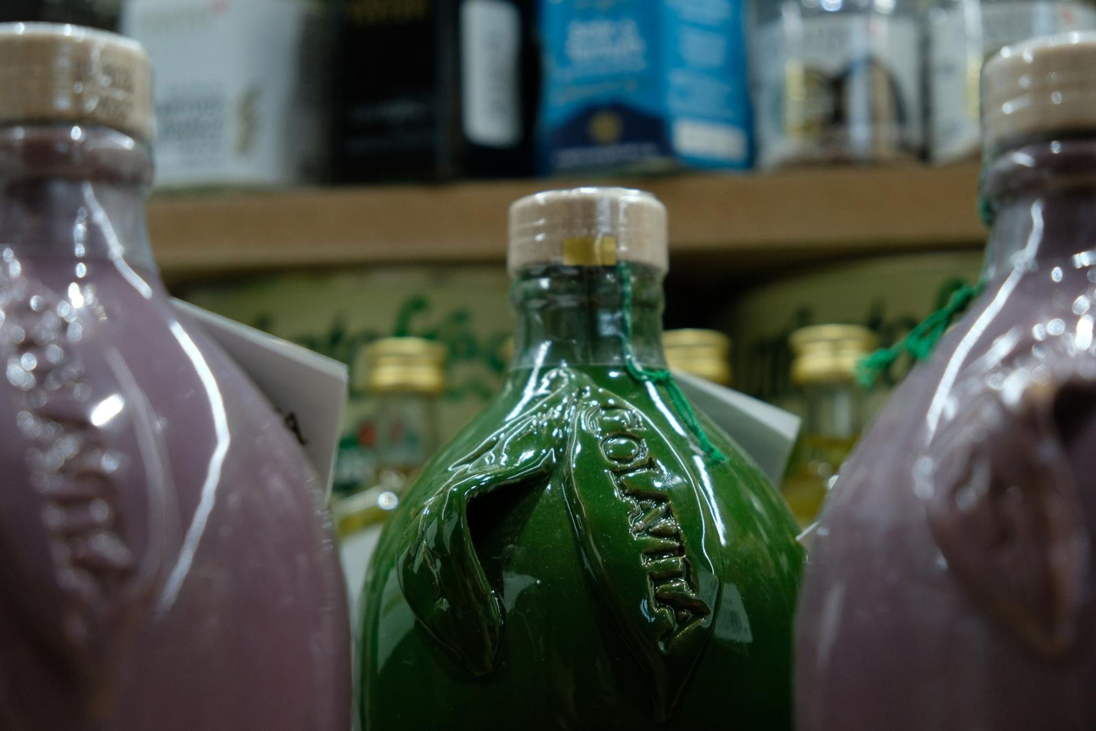 Ceramic olive oil bottles in green and mauve on the shelf