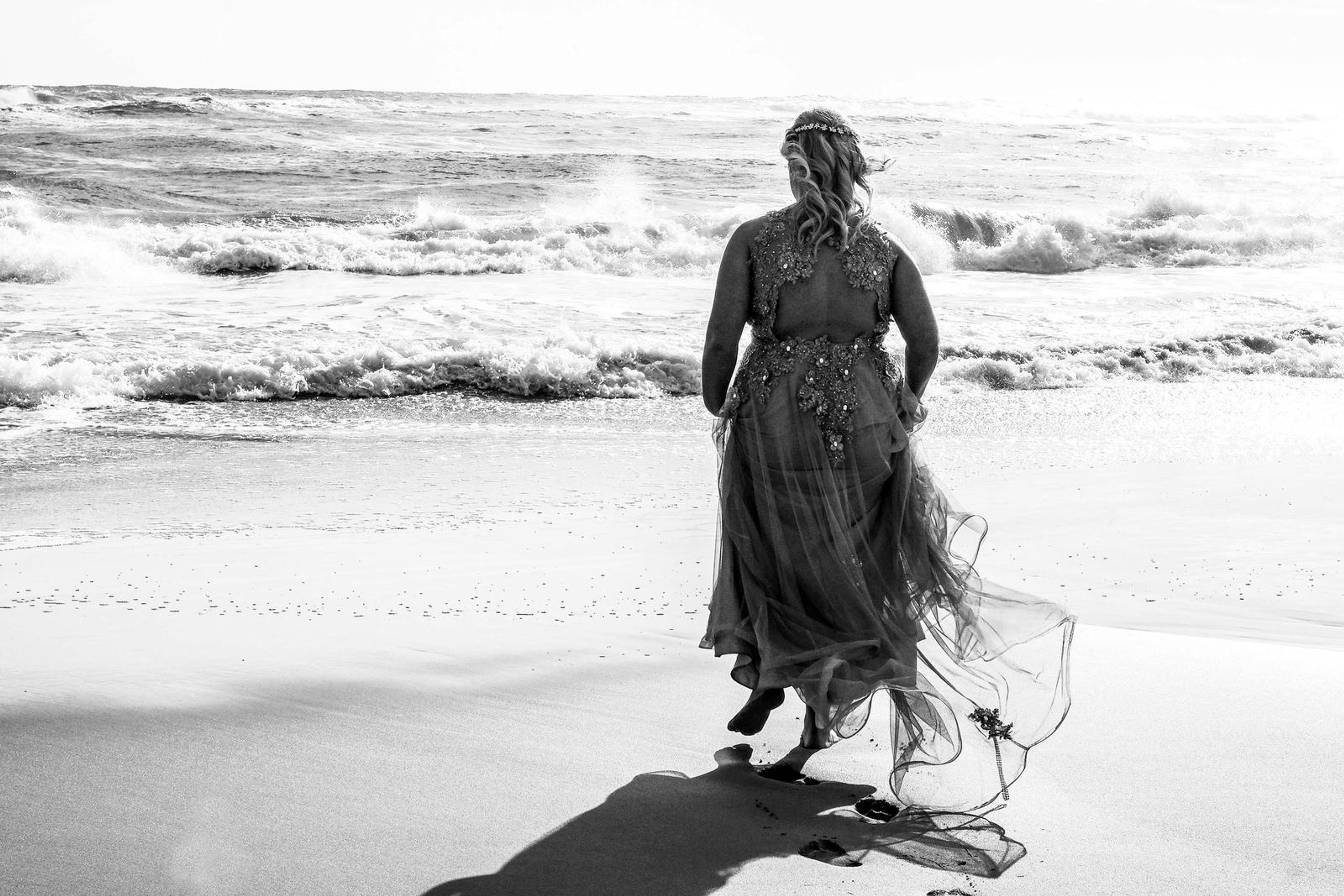 Black and white back view walking through the surf