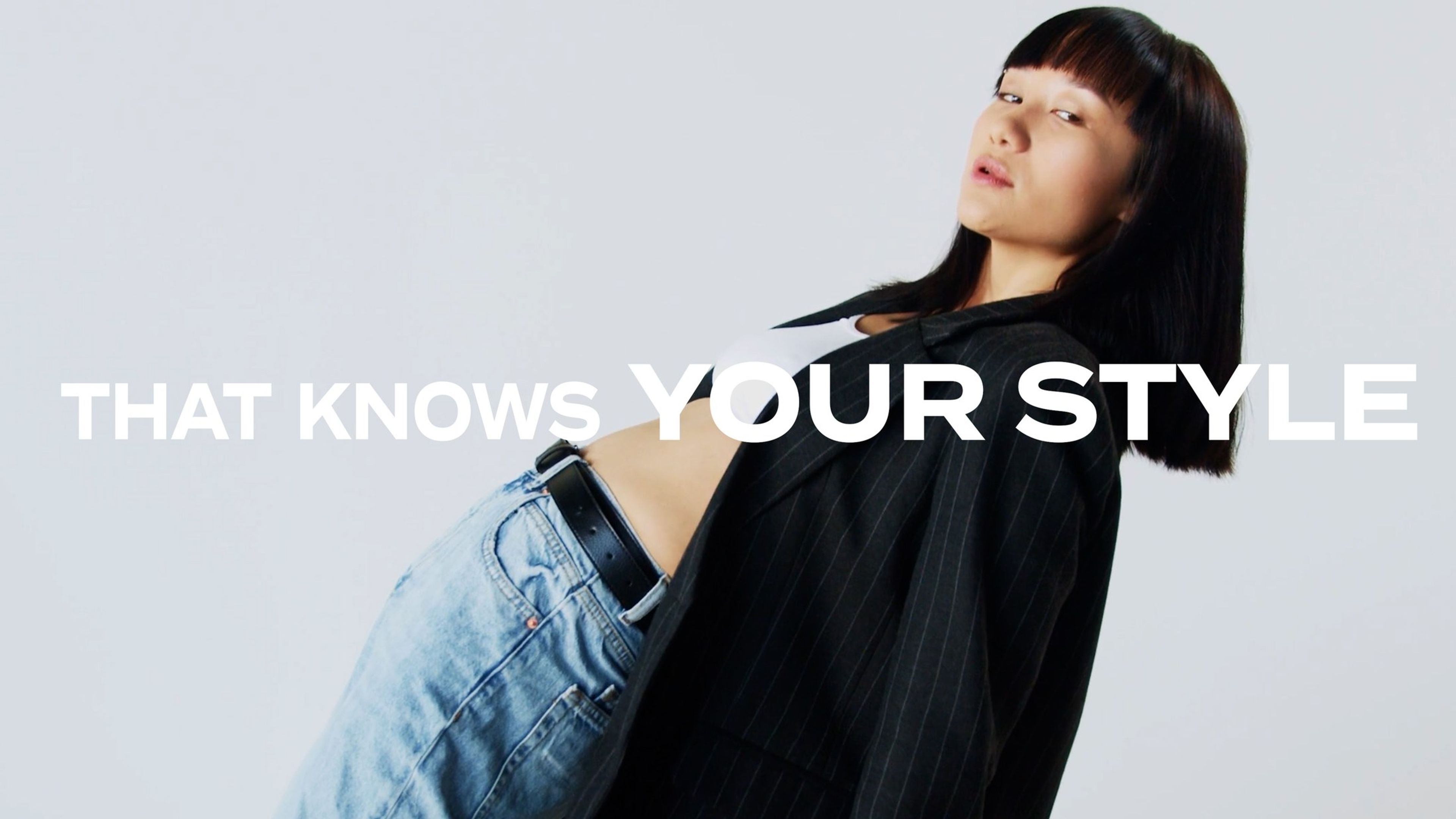 Woman in a black jacket and jeans against a pale backdrop, with the text 'That knows your style'