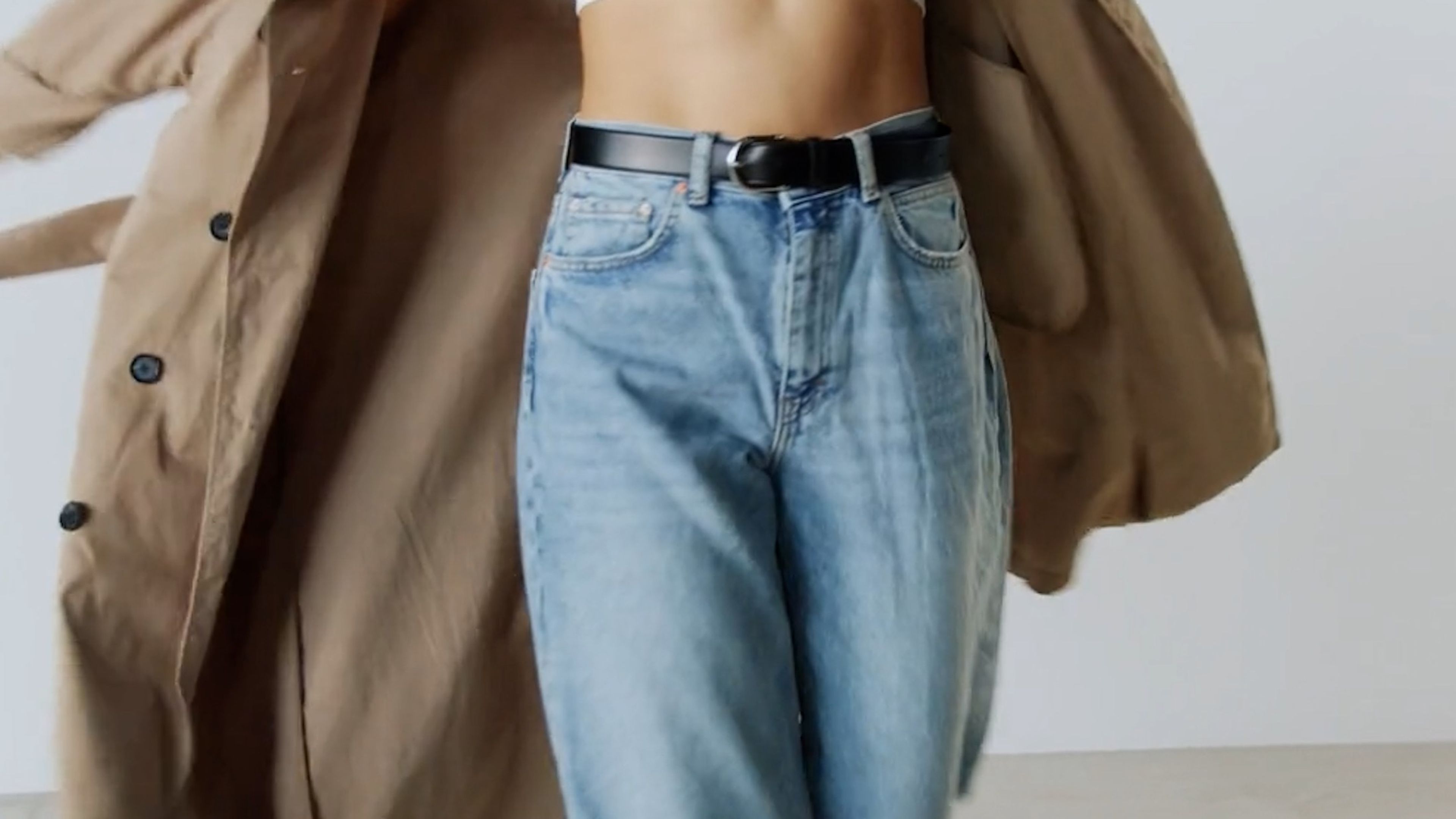 Close-up of a tan coat and light denim jeans in motion