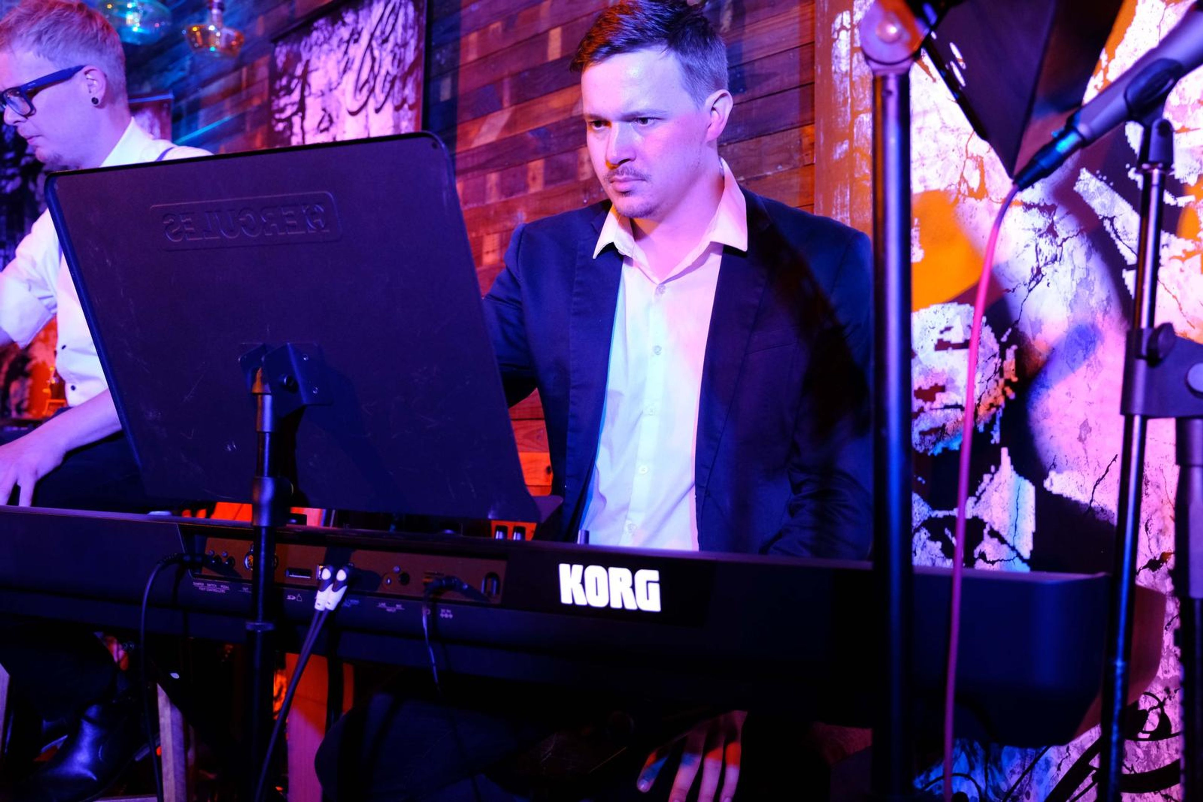 Keyboard player in a blazer playing a Korg keyboard