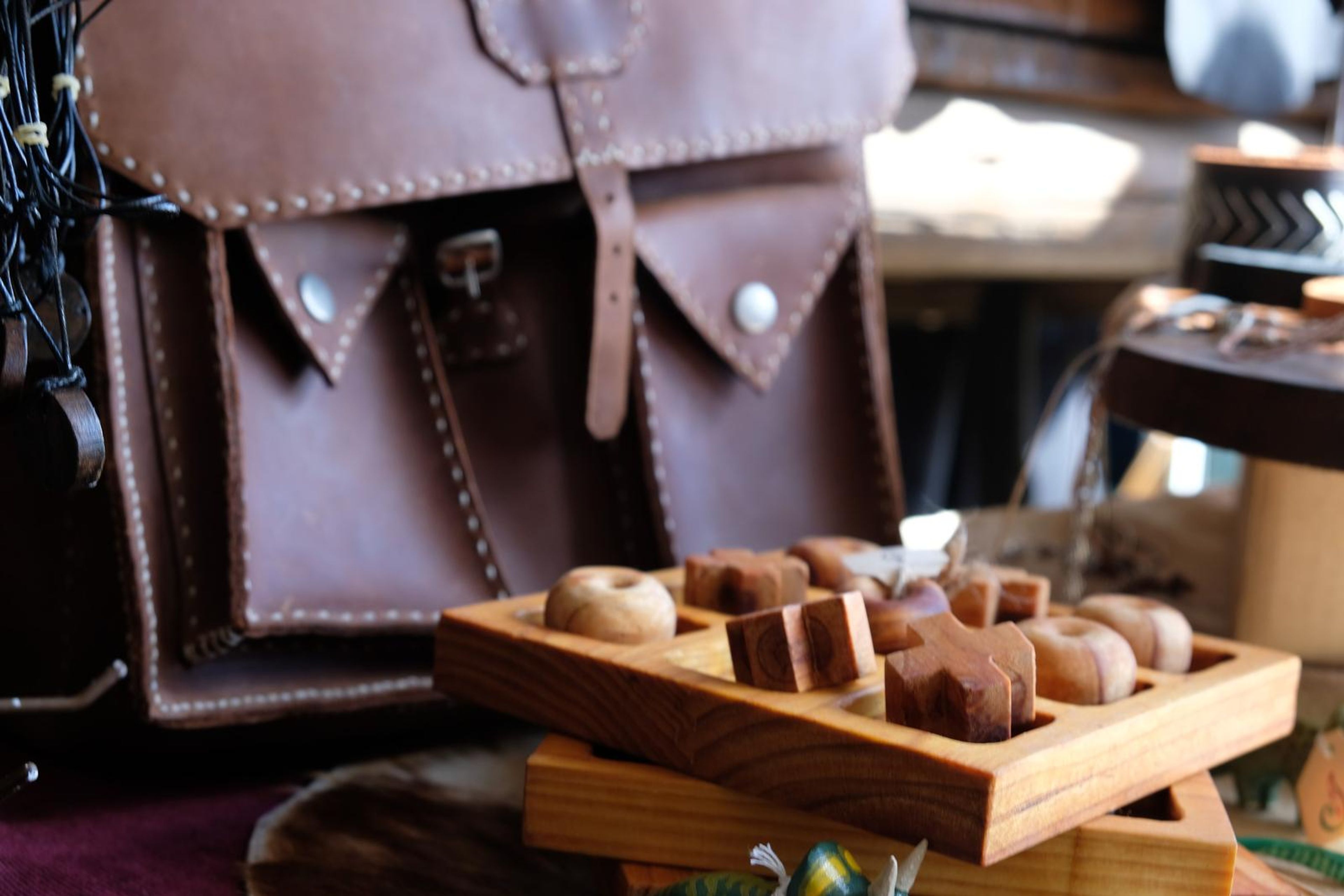 Brown leather satchel with a hand-carved wooden game in front
