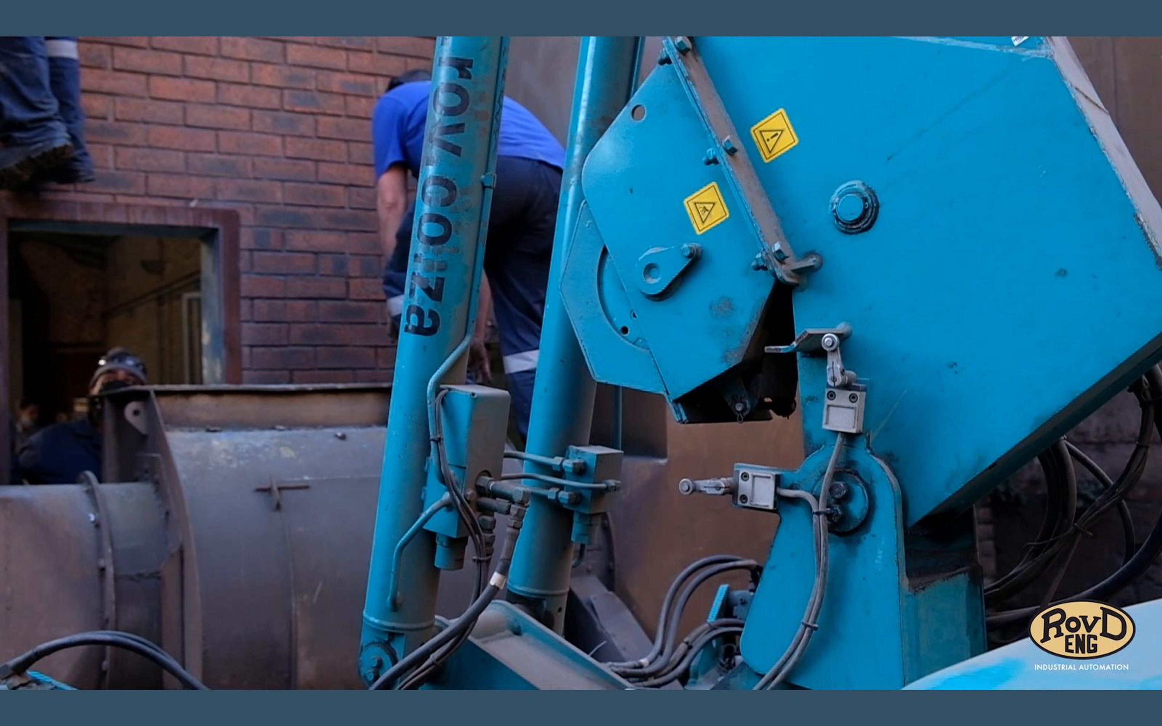 Blue crane hoist beside a brick wall