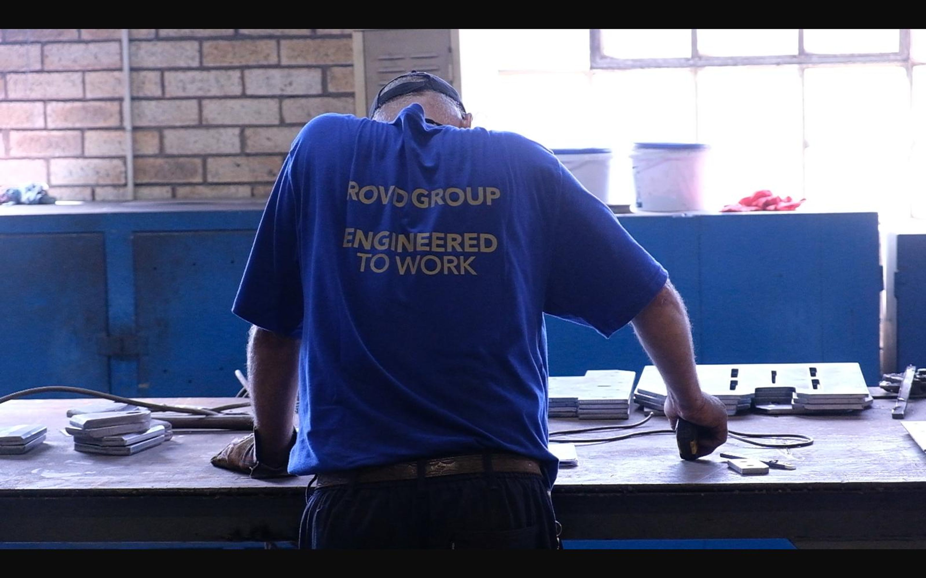 Fabricator at a steel bench seen from behind