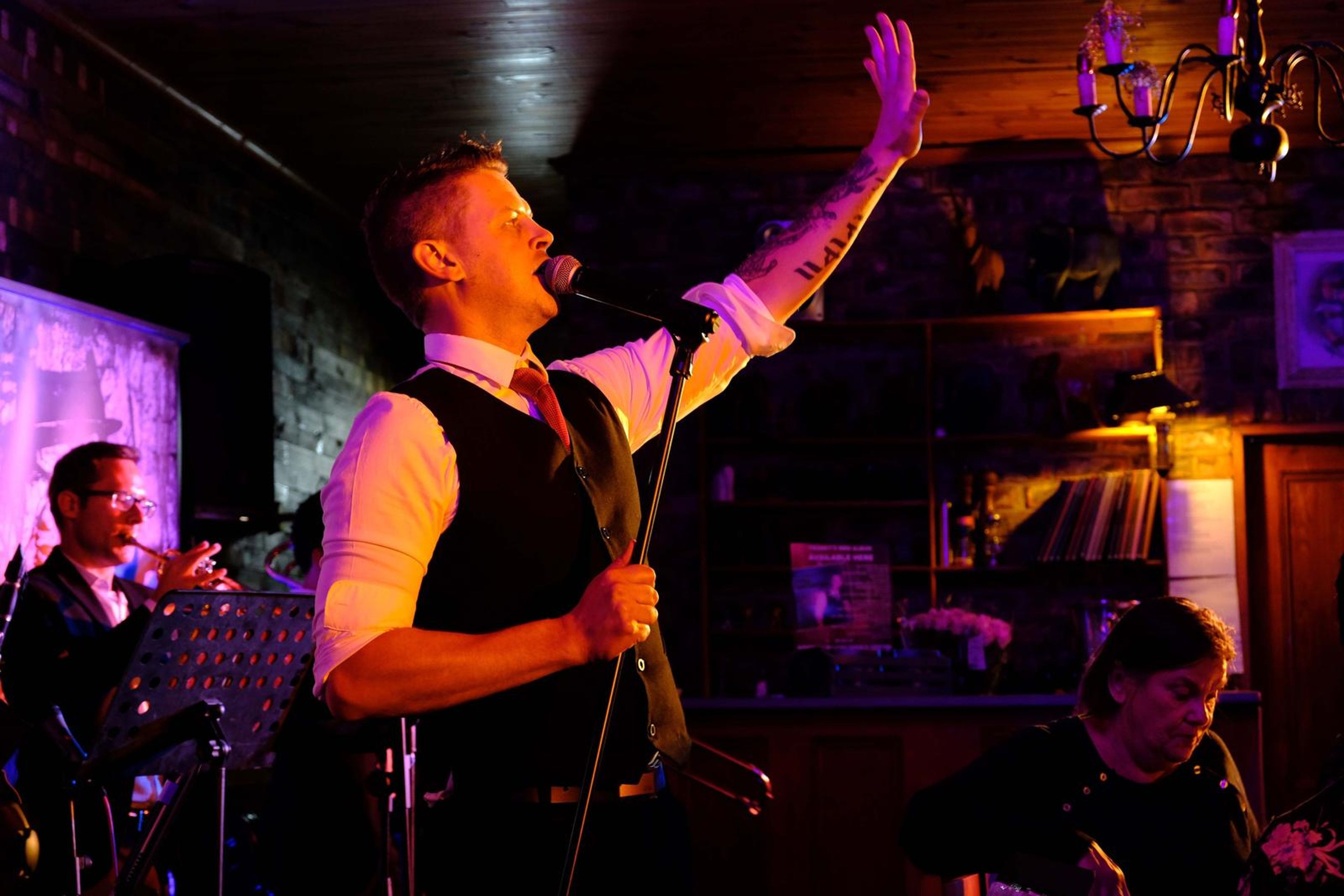 Singer with his arm raised high, holding the microphone stand