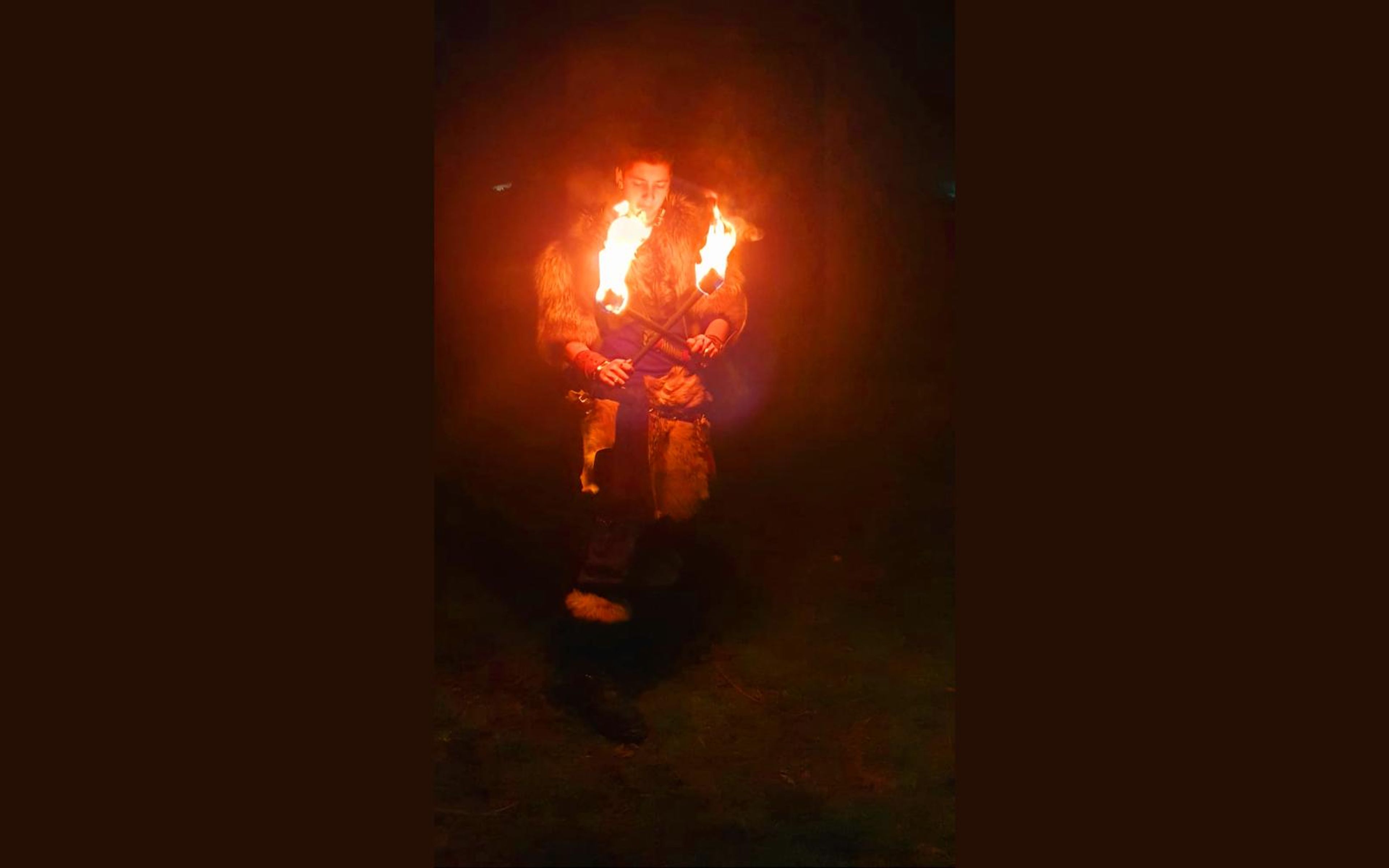 Barbarian in fur holding a flaming torch at night, phone photo from the shoot