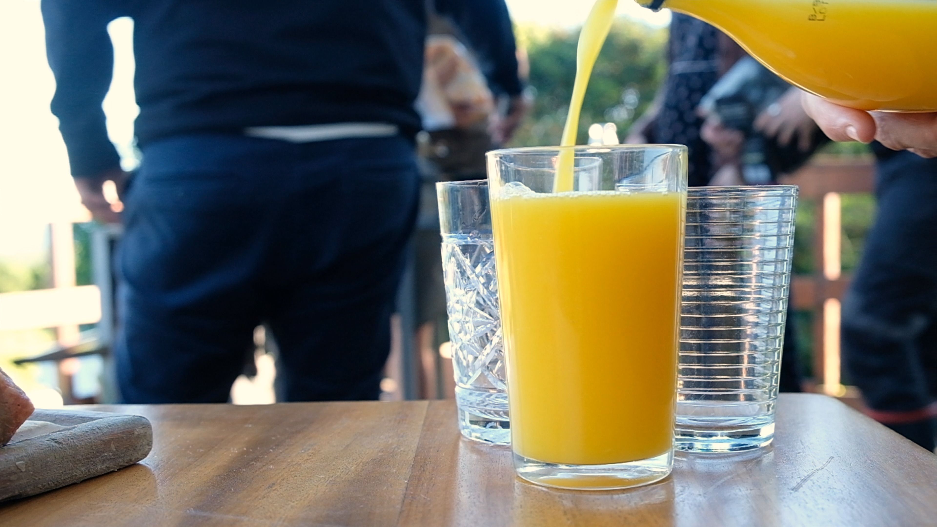 Glass filling with orange juice on an outdoor table