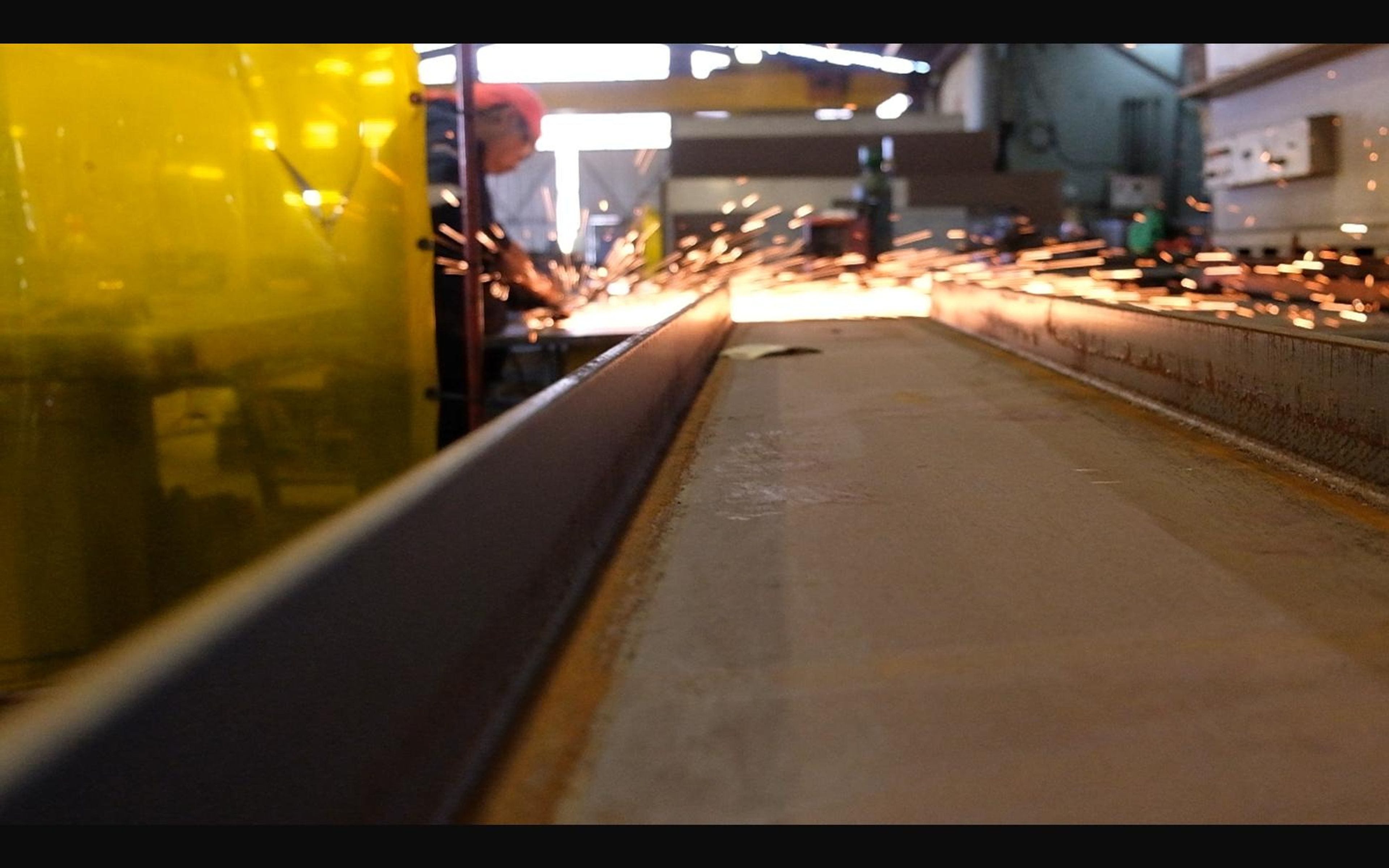 Sparks running along a steel beam from grinding