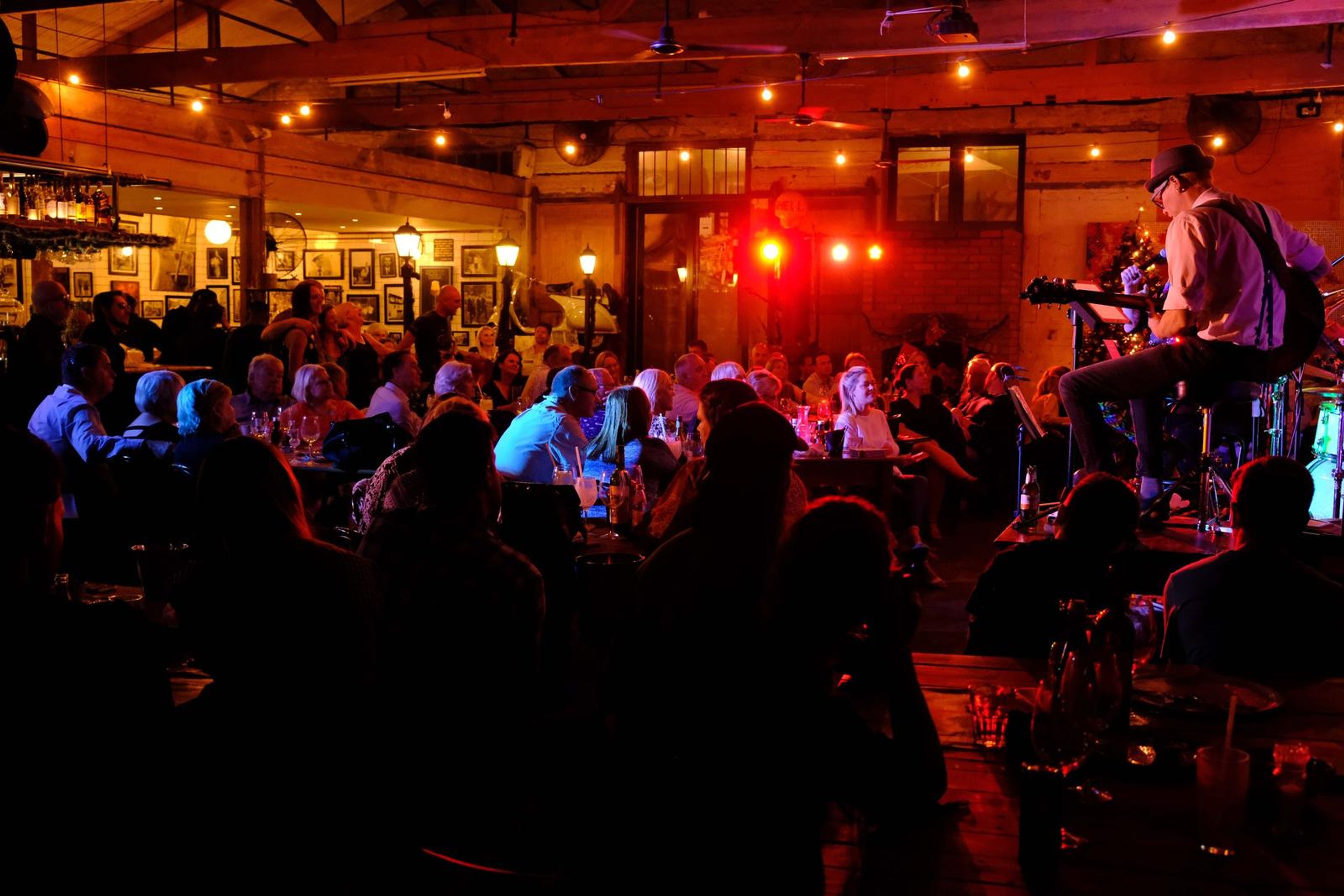 Wide view of the band lit in red across the packed restaurant