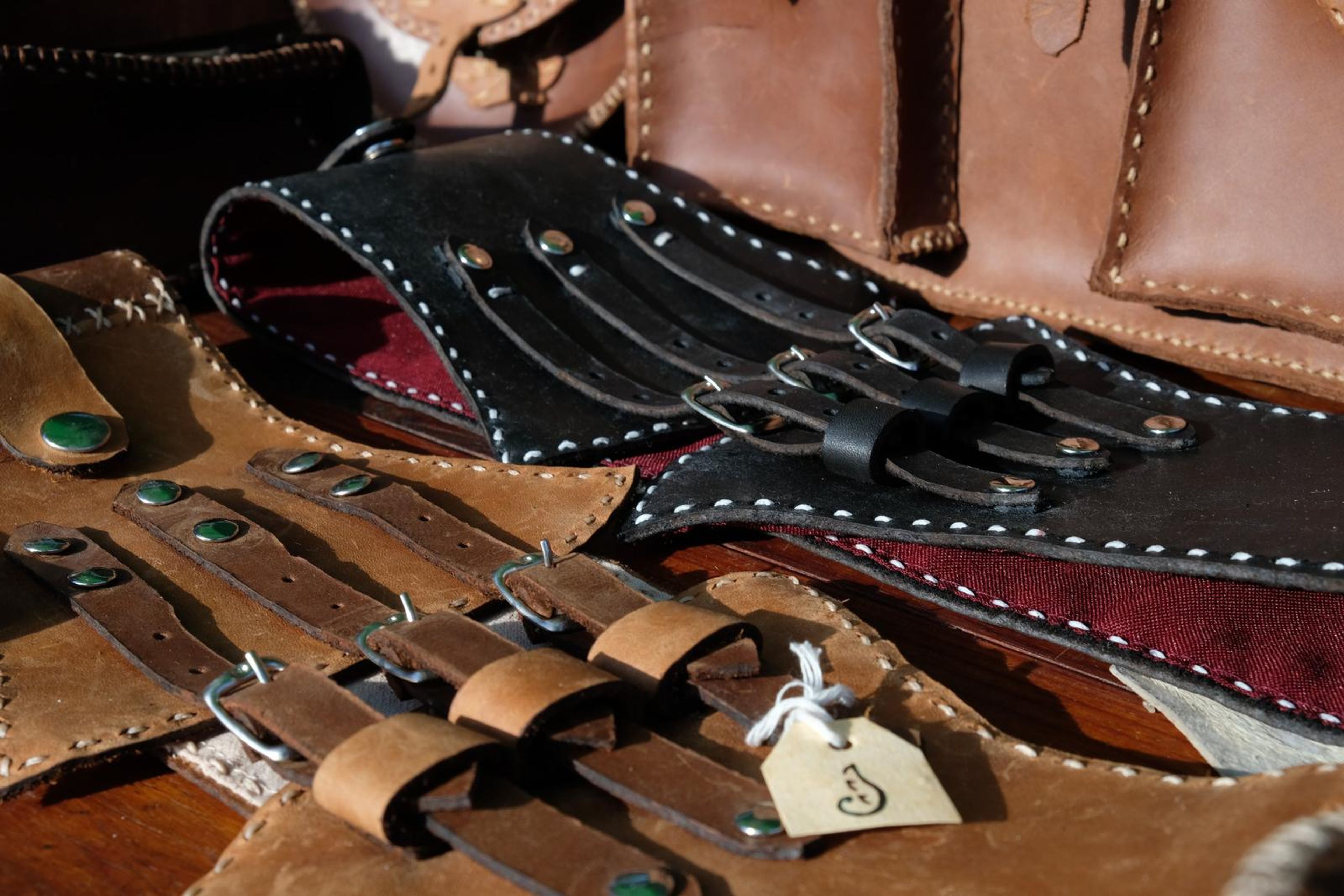 Tan and black leather corset belts and satchels laid out at the Juuks stall