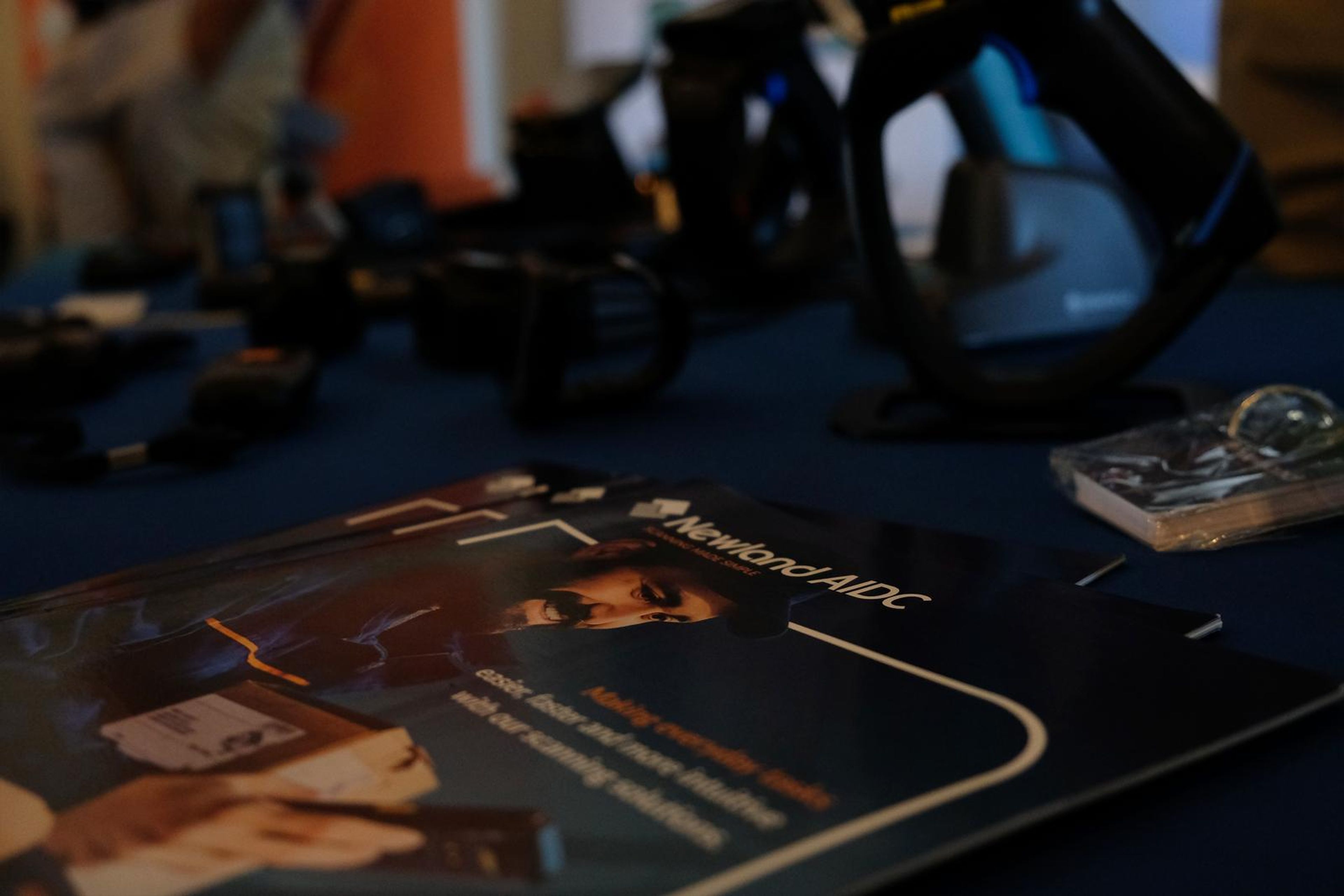 Newland AIDC handheld scanners and a brochure on a blue table