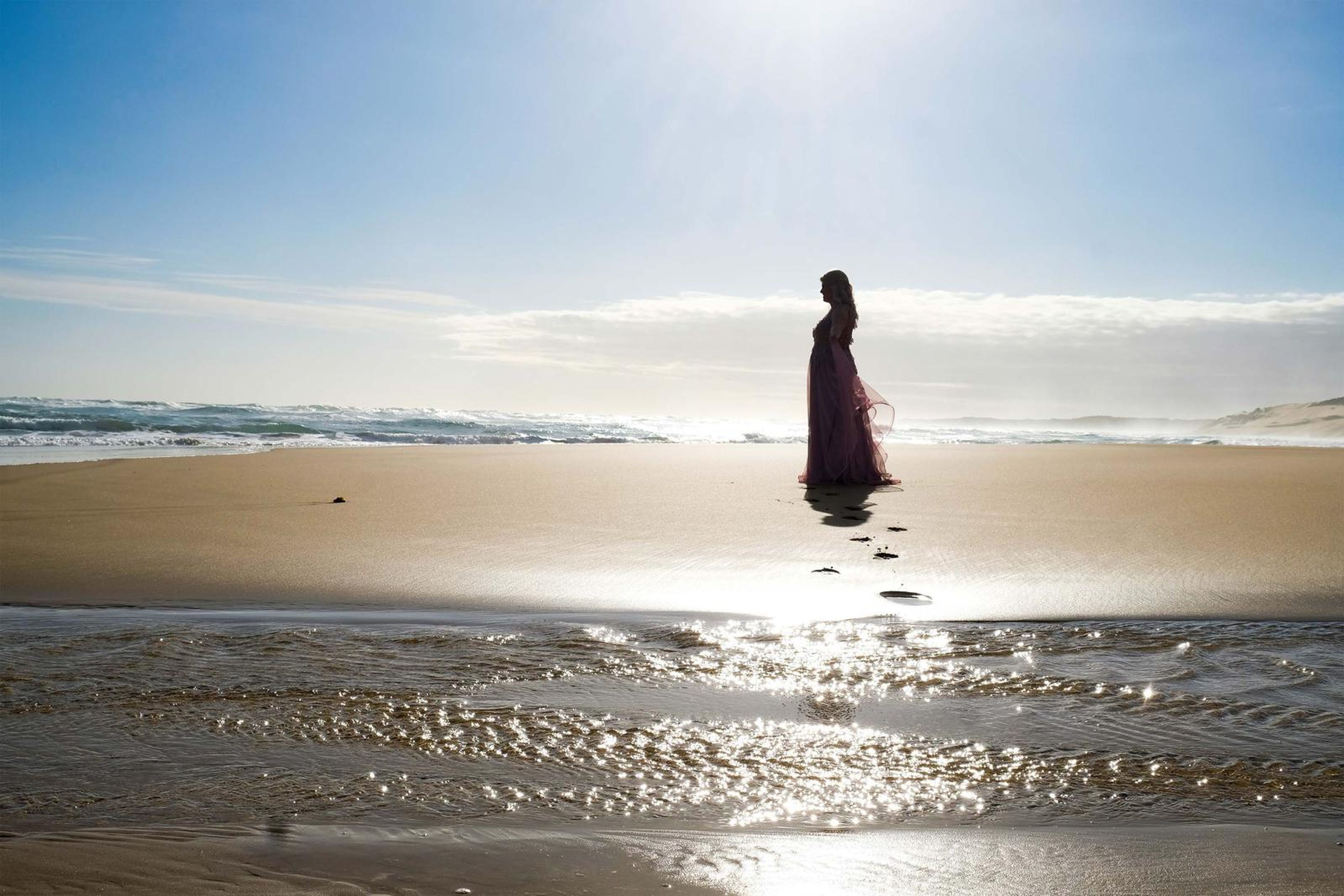 Silhouette on the wet sand with the sun behind