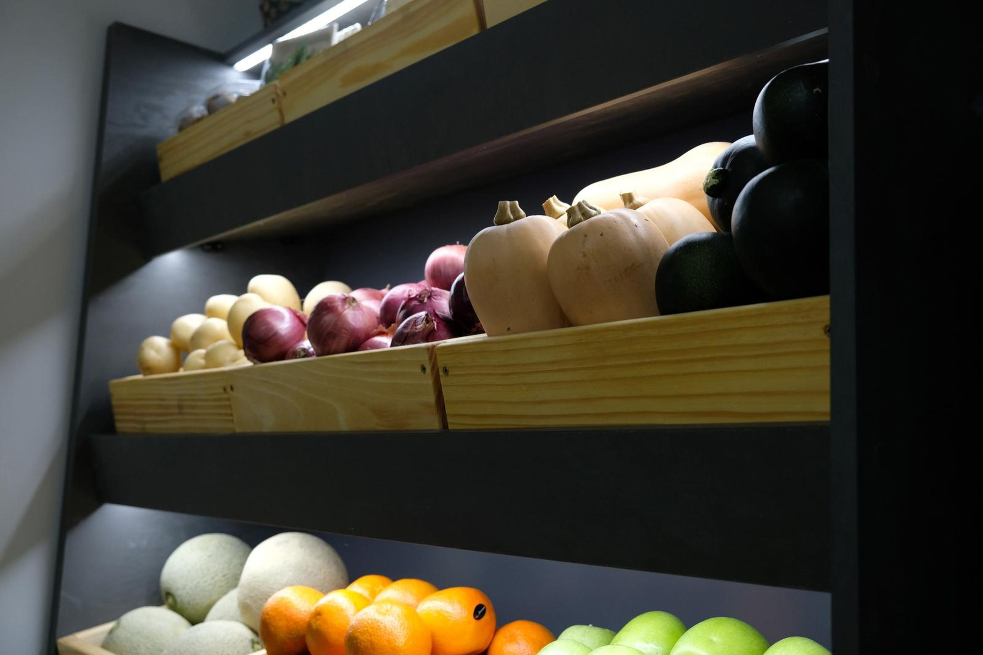 Wide view of the produce shelves with butternut, onions, oranges and apples