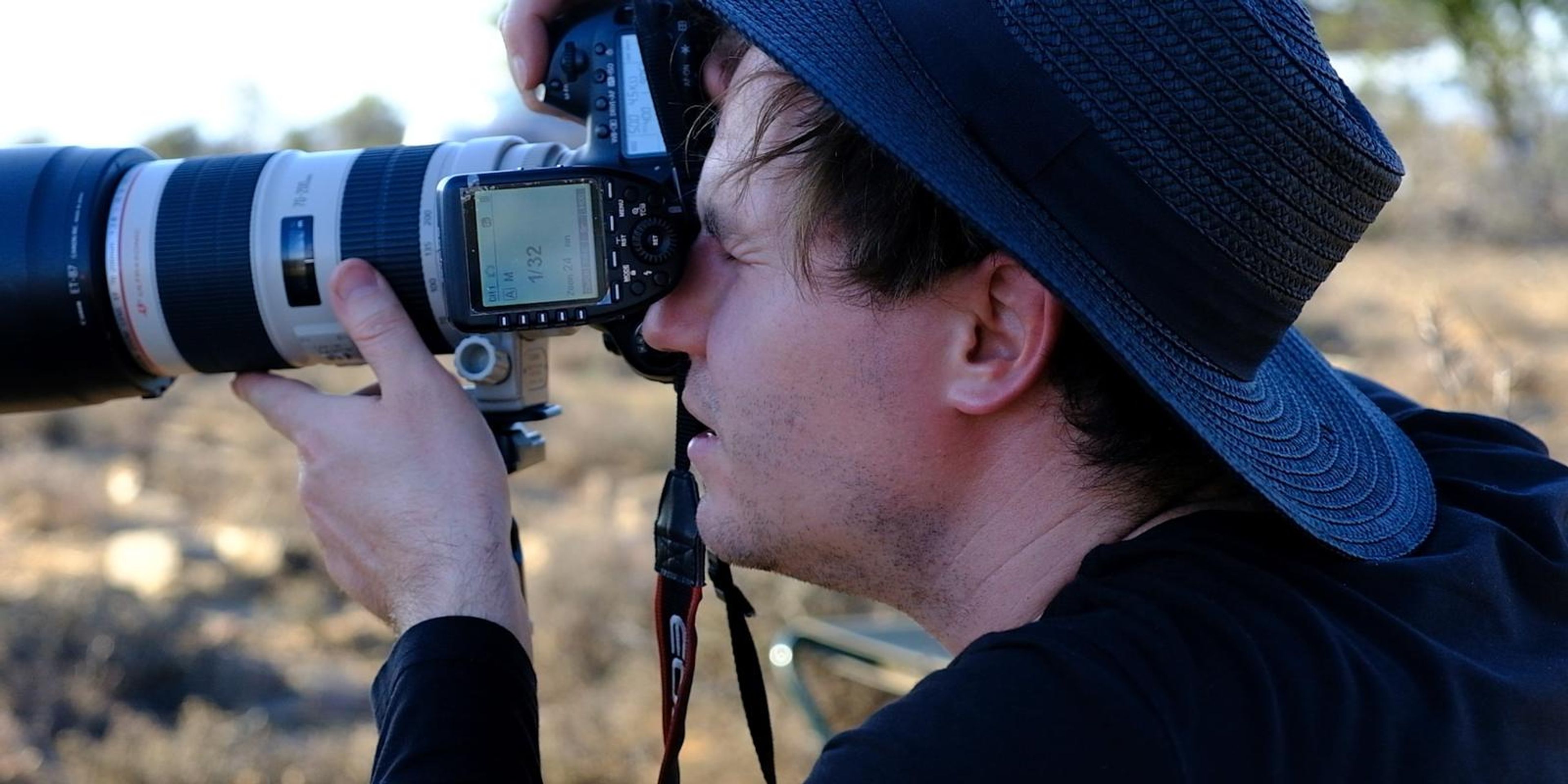 Close view of the photographer lining up a shot through a long lens