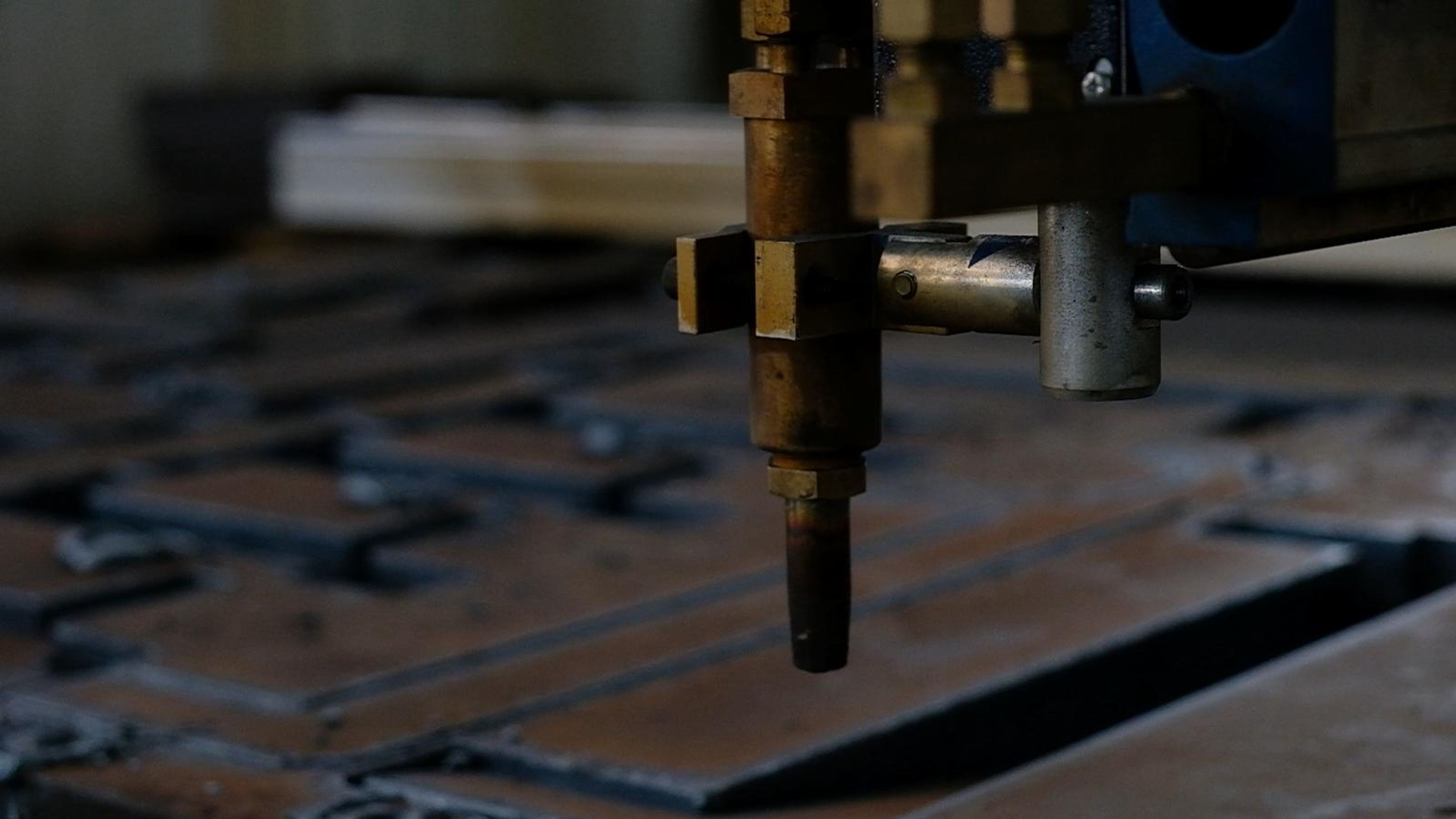 Plasma torch head above a steel plate with cut profiles