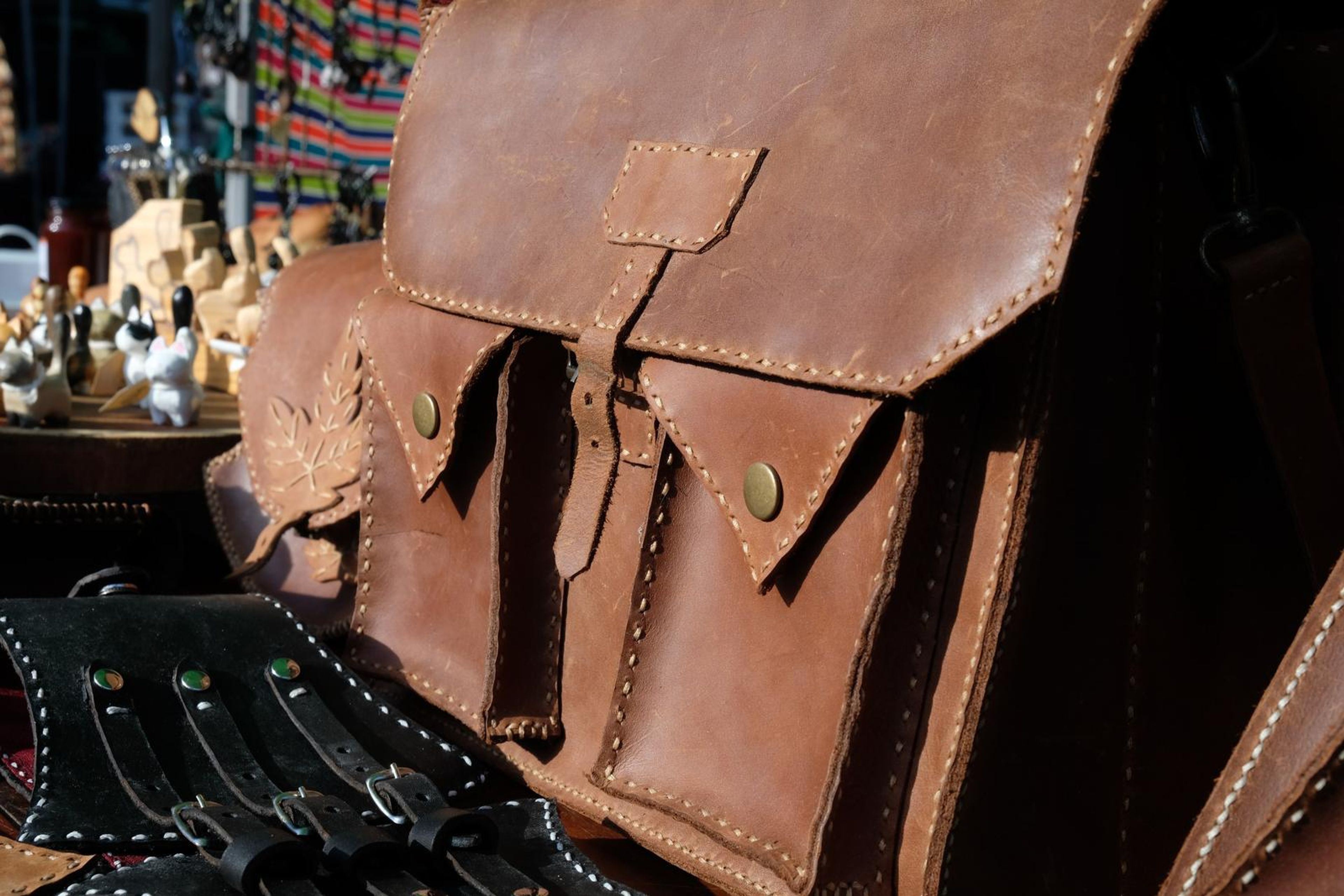 Tan and black leather corset belts and satchels laid out at the Juuks stall