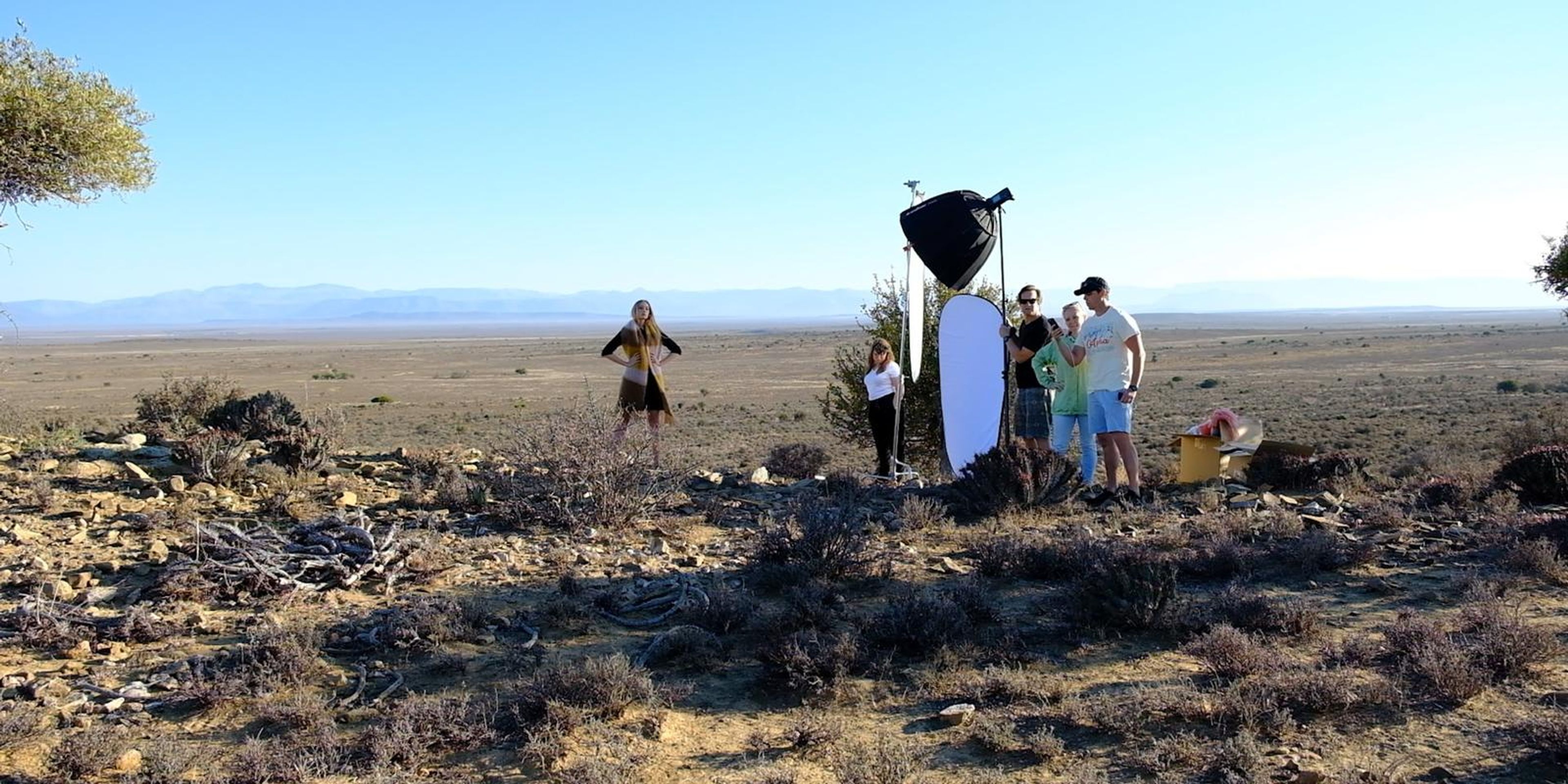 Wide view of the crew and model on the hilltop with a softbox and reflector