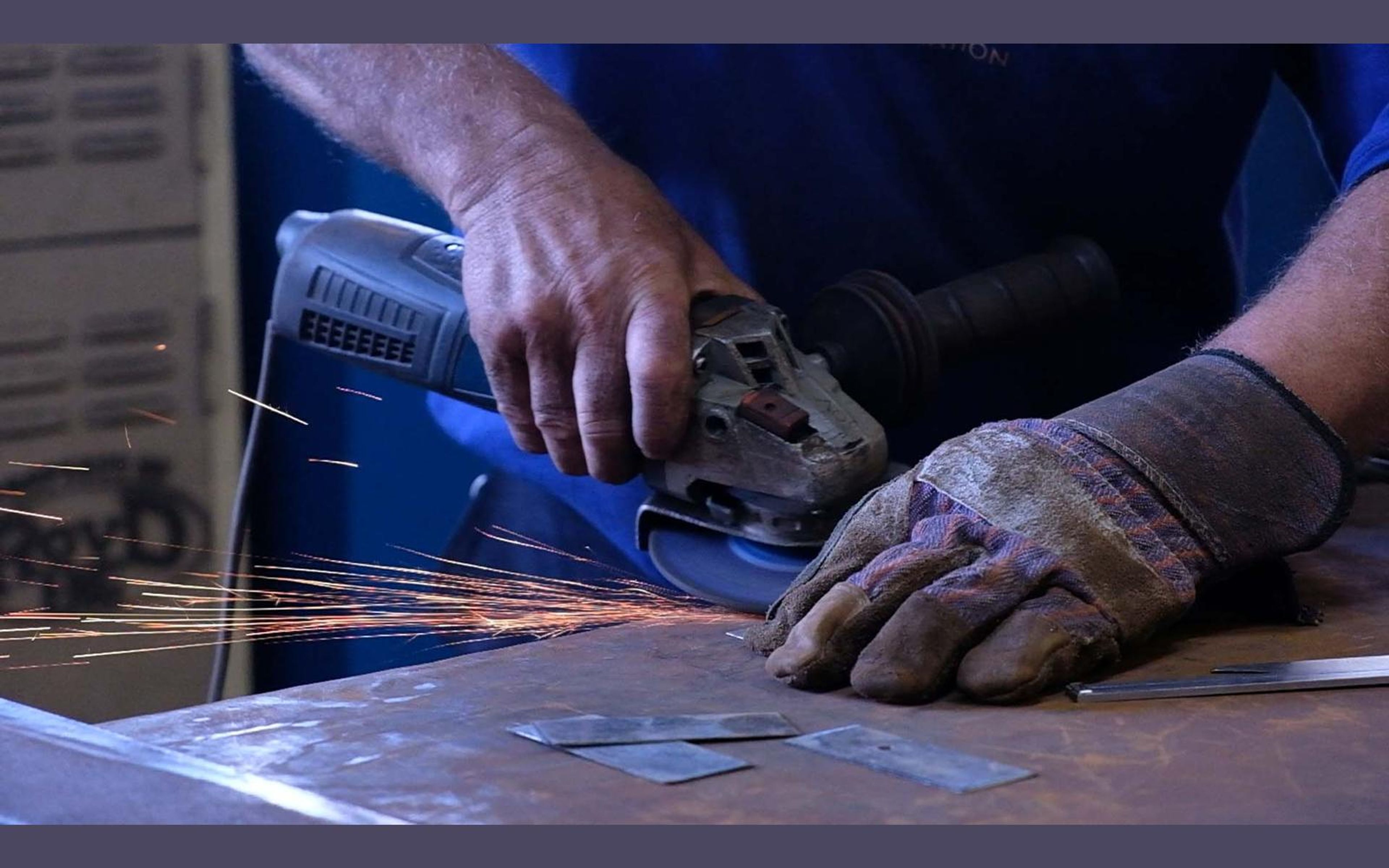 Fabricator grinding a steel edge with orange sparks