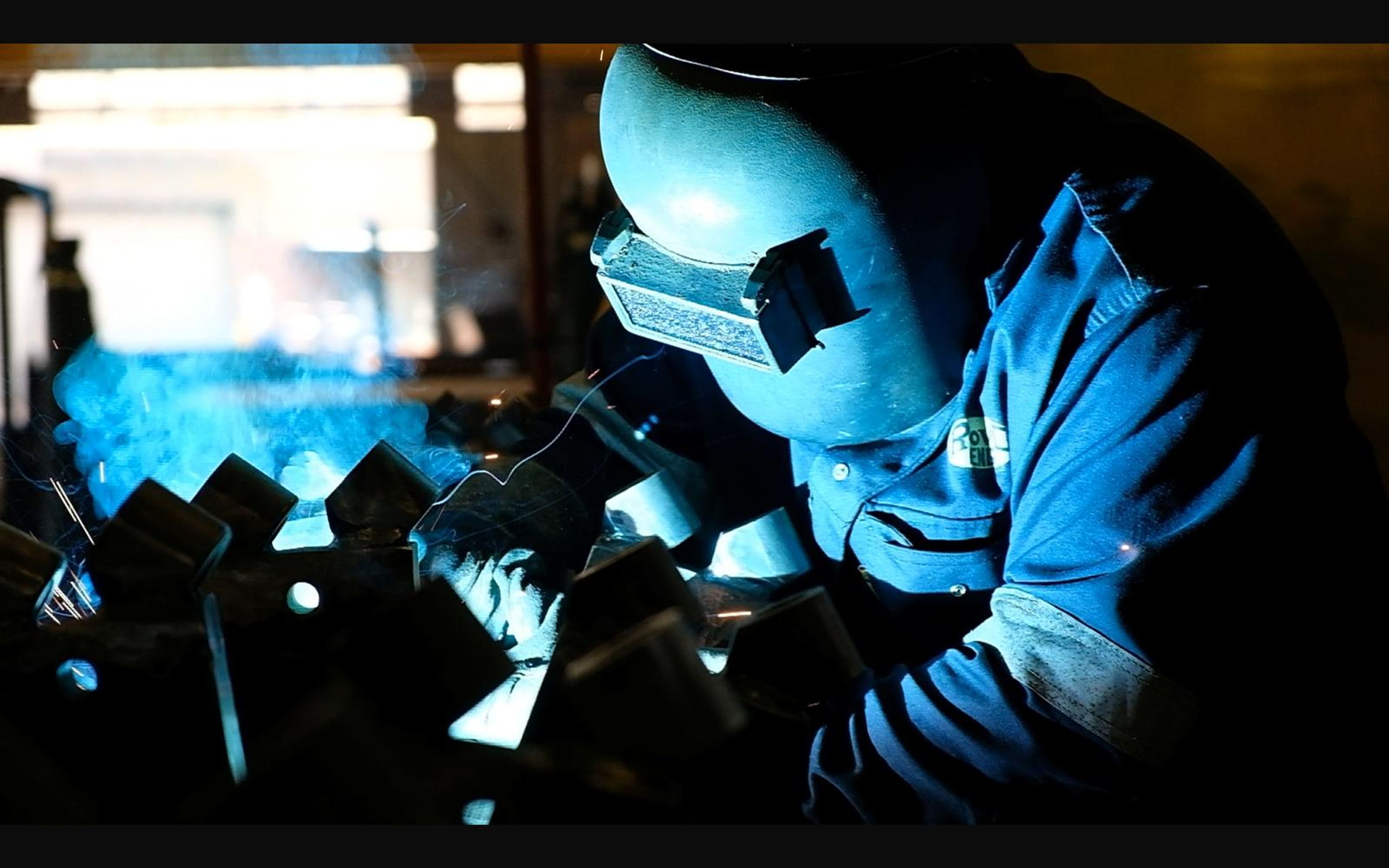Welder in a helmet working on brackets