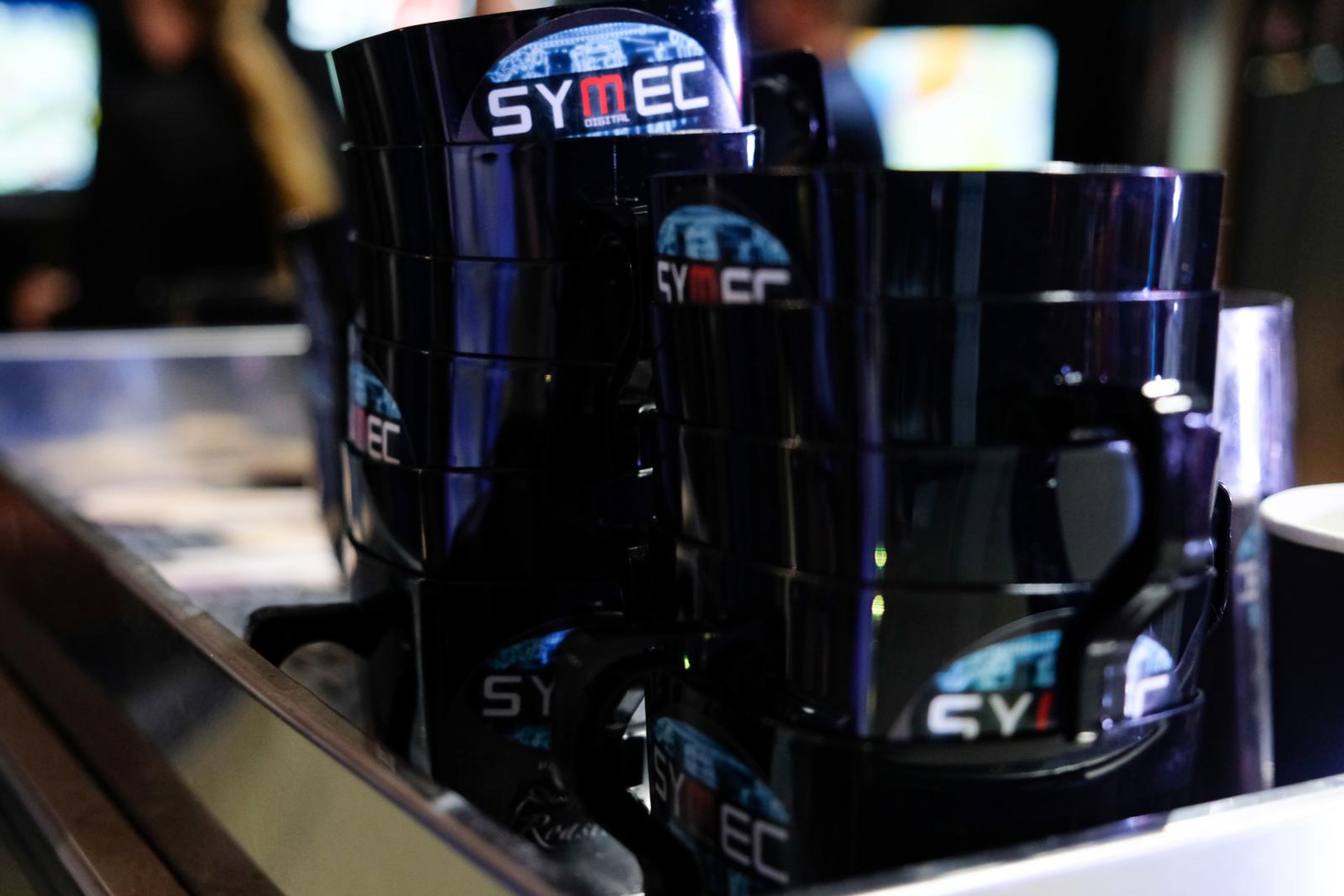 Stack of black Symec-branded coffee cups