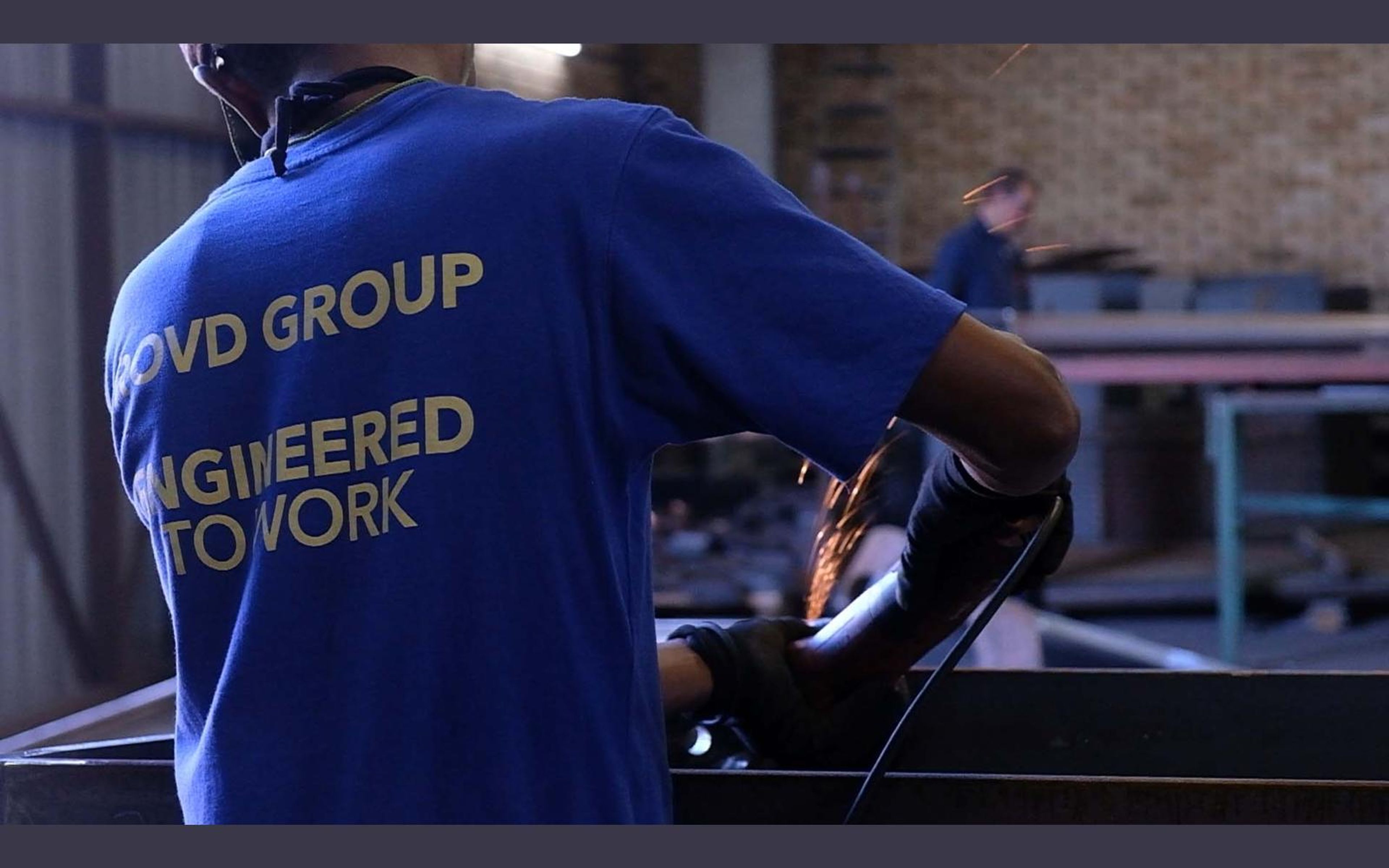 Fabricator in a ROVD shirt working at a steel bench