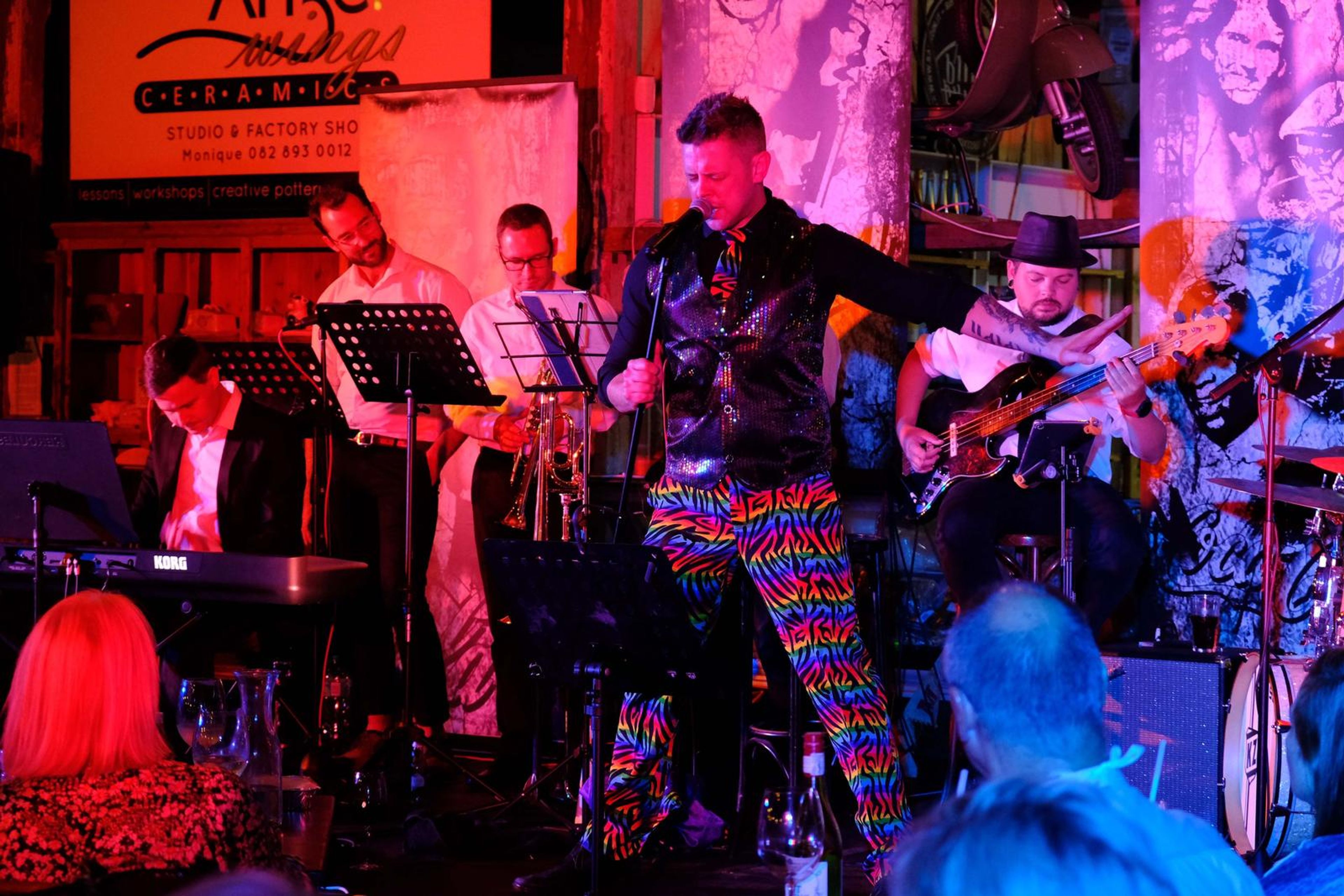 Singer in rainbow trousers dancing in front of the band