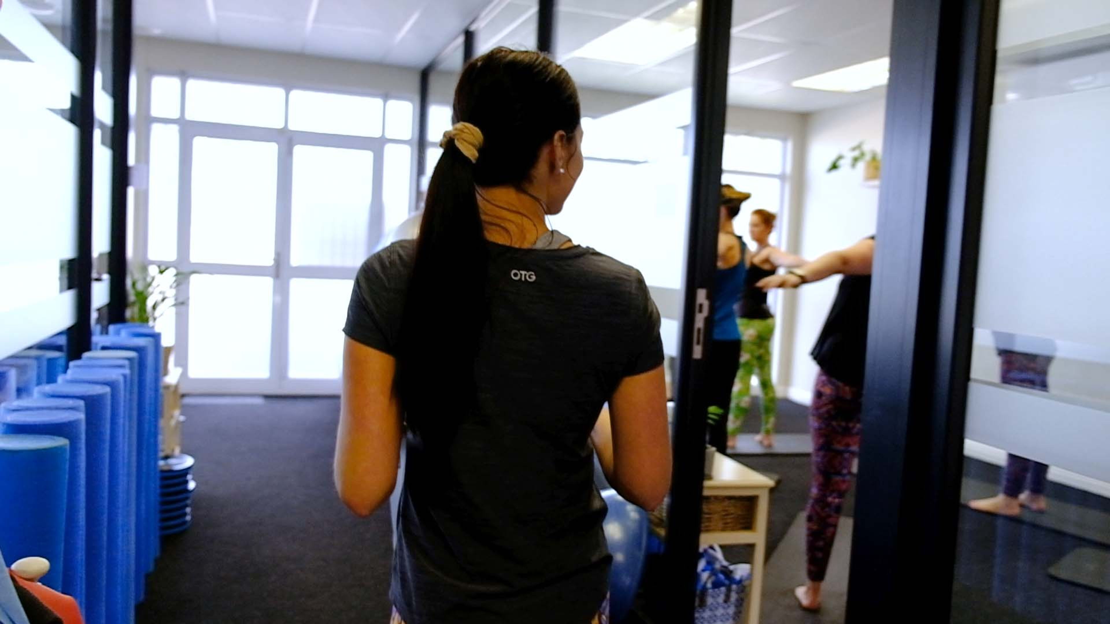 Staff member seen from behind walking through the studio, blue foam rollers lining the floor