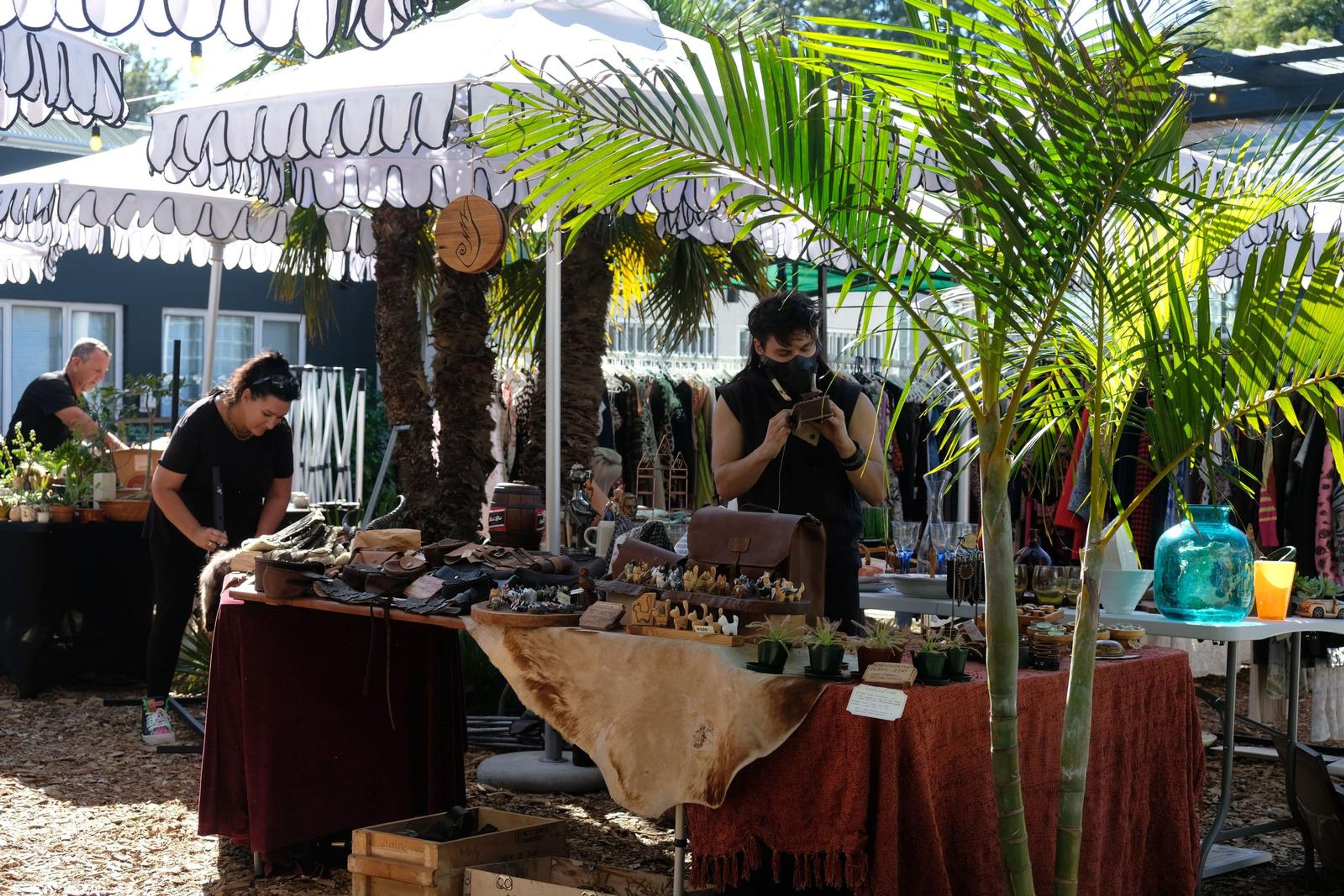 Juuks market stall under a palm tree at Filthy McNasty's with leather goods and carvings on display