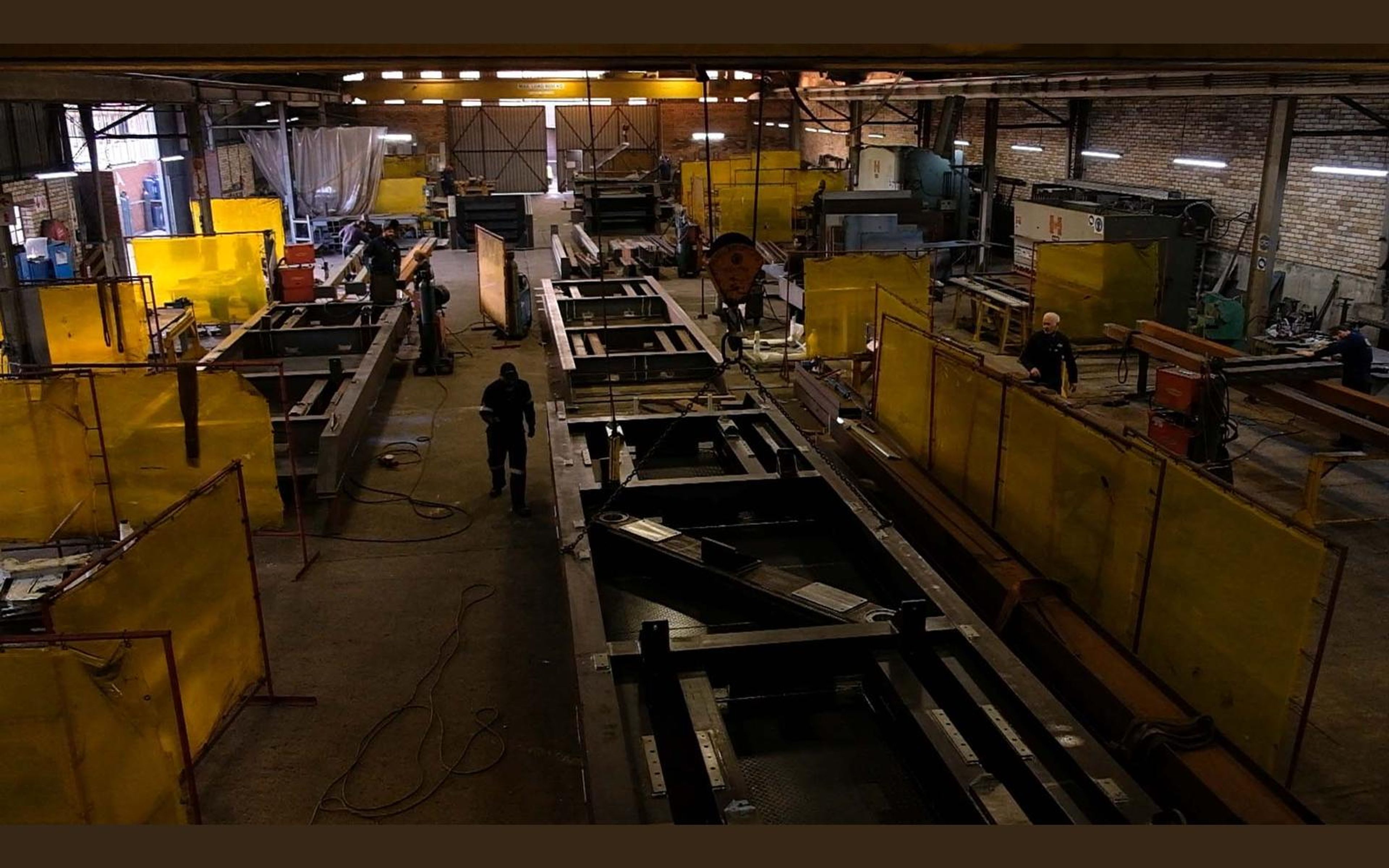 Fabrication bay with yellow welding screens and steel sections