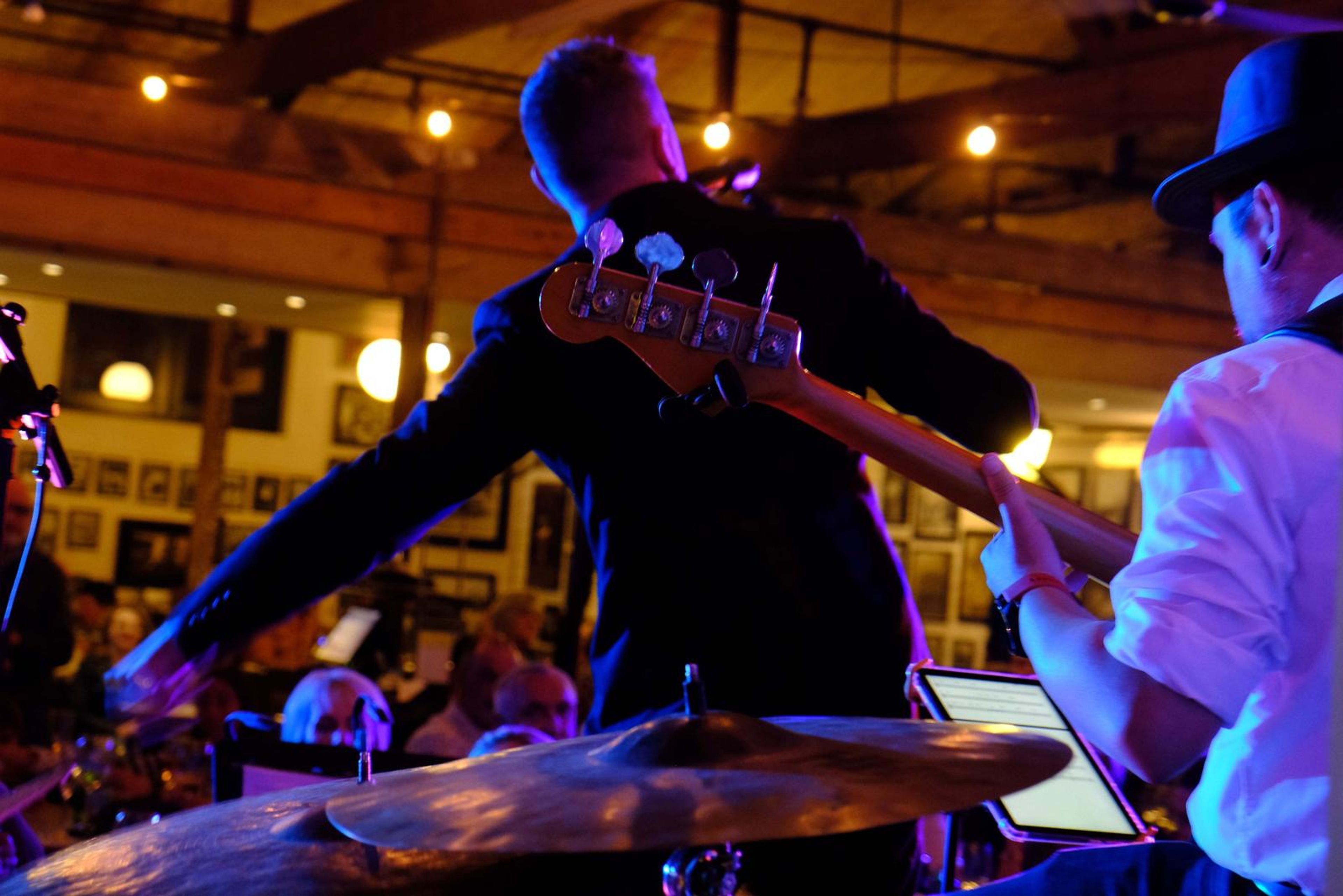 Bass player and singer on stage seen from behind the drums