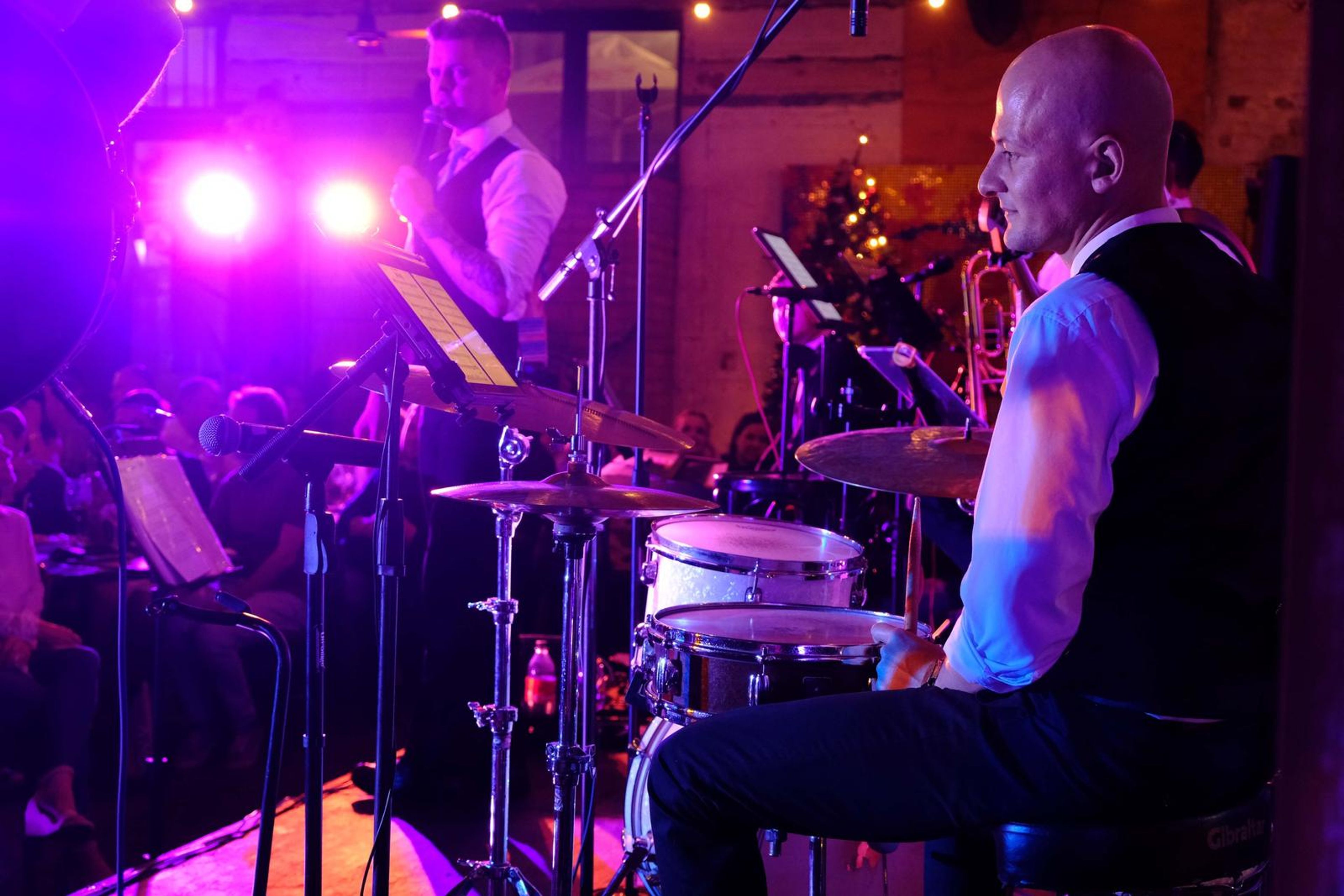 Drummer and singer playing in purple stage light