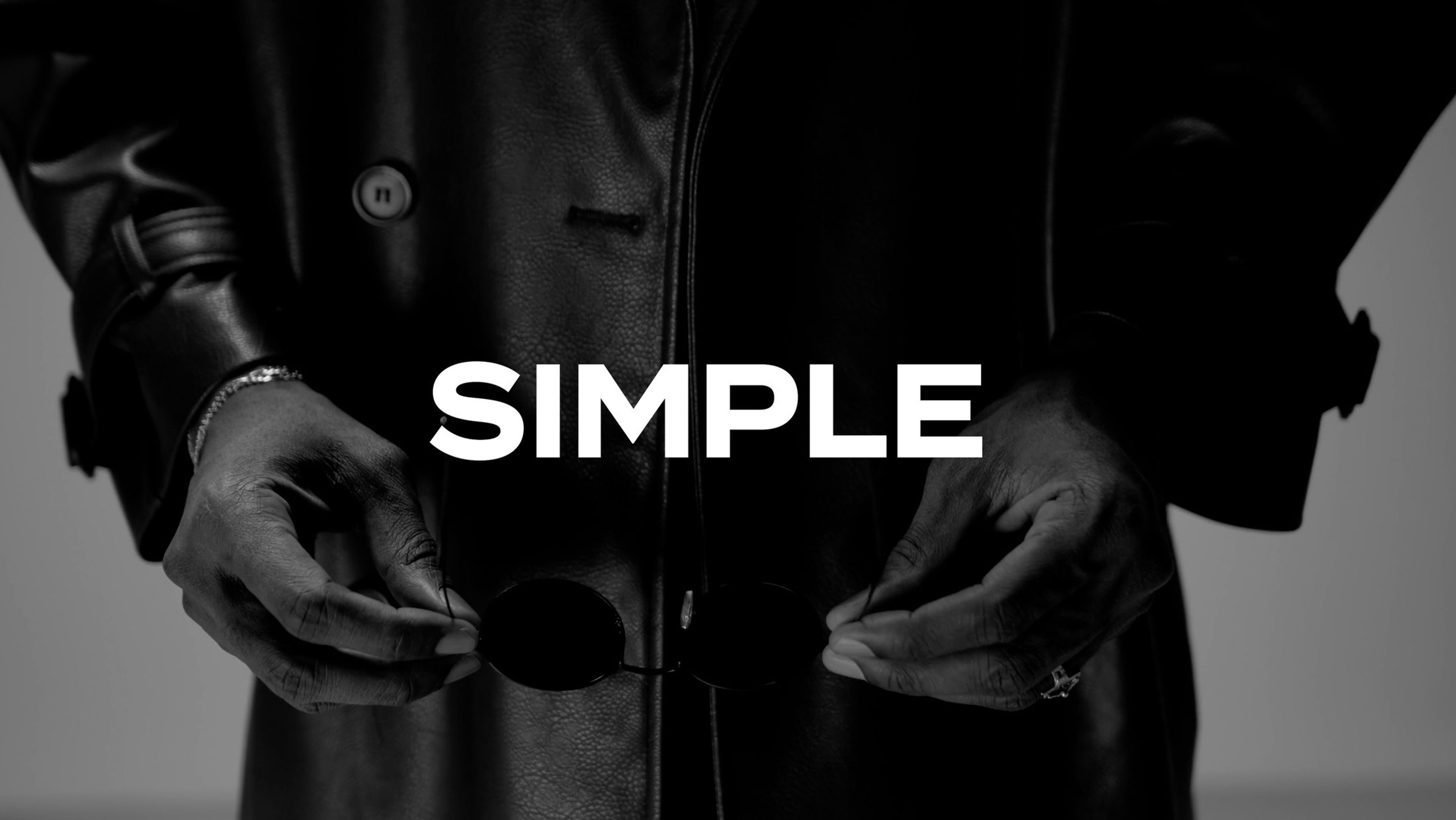 Hands tucked into a dark leather jacket, with the text 'Simple'