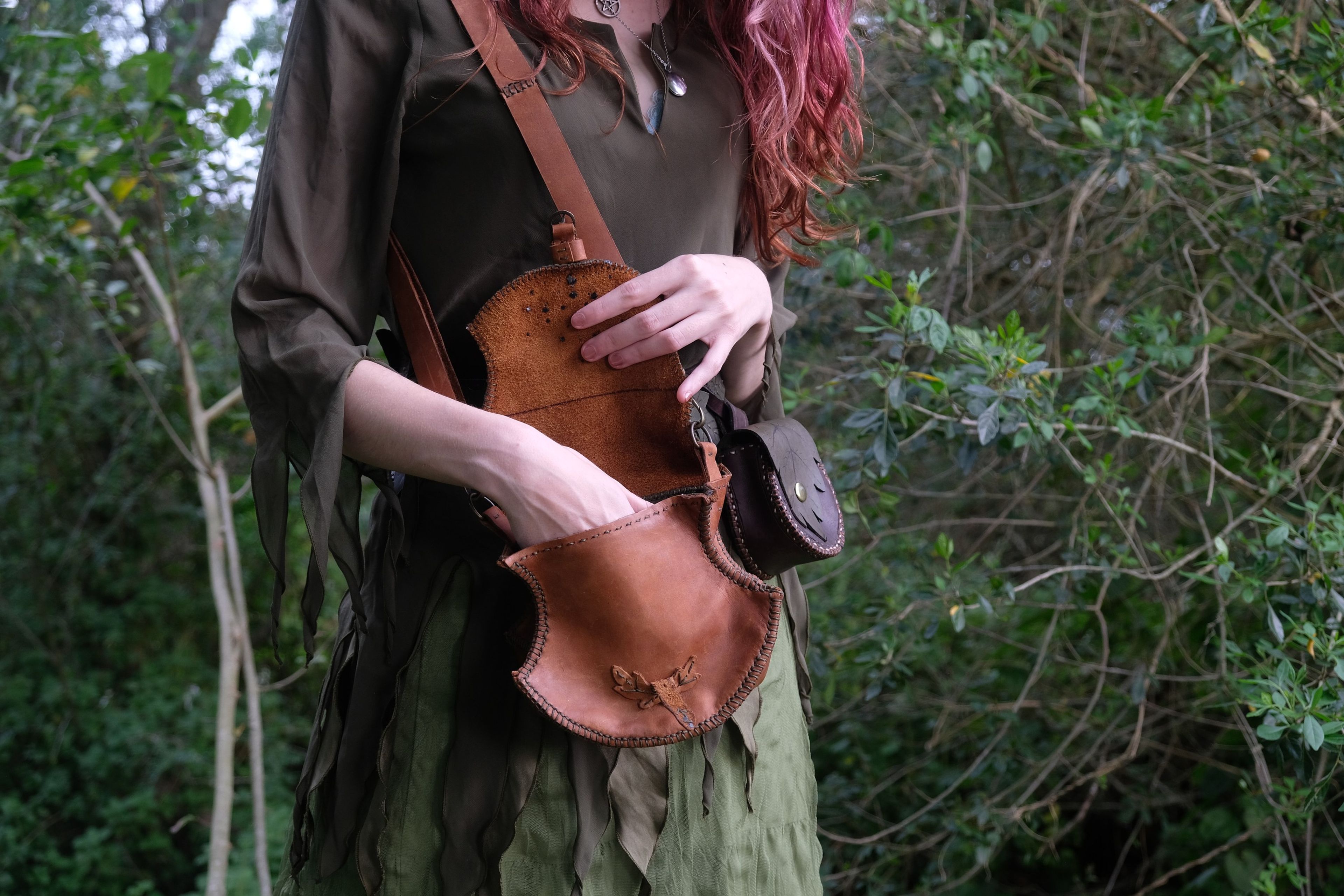 Woman in a green dress carrying a tan leather bag, with a small pouch on her belt