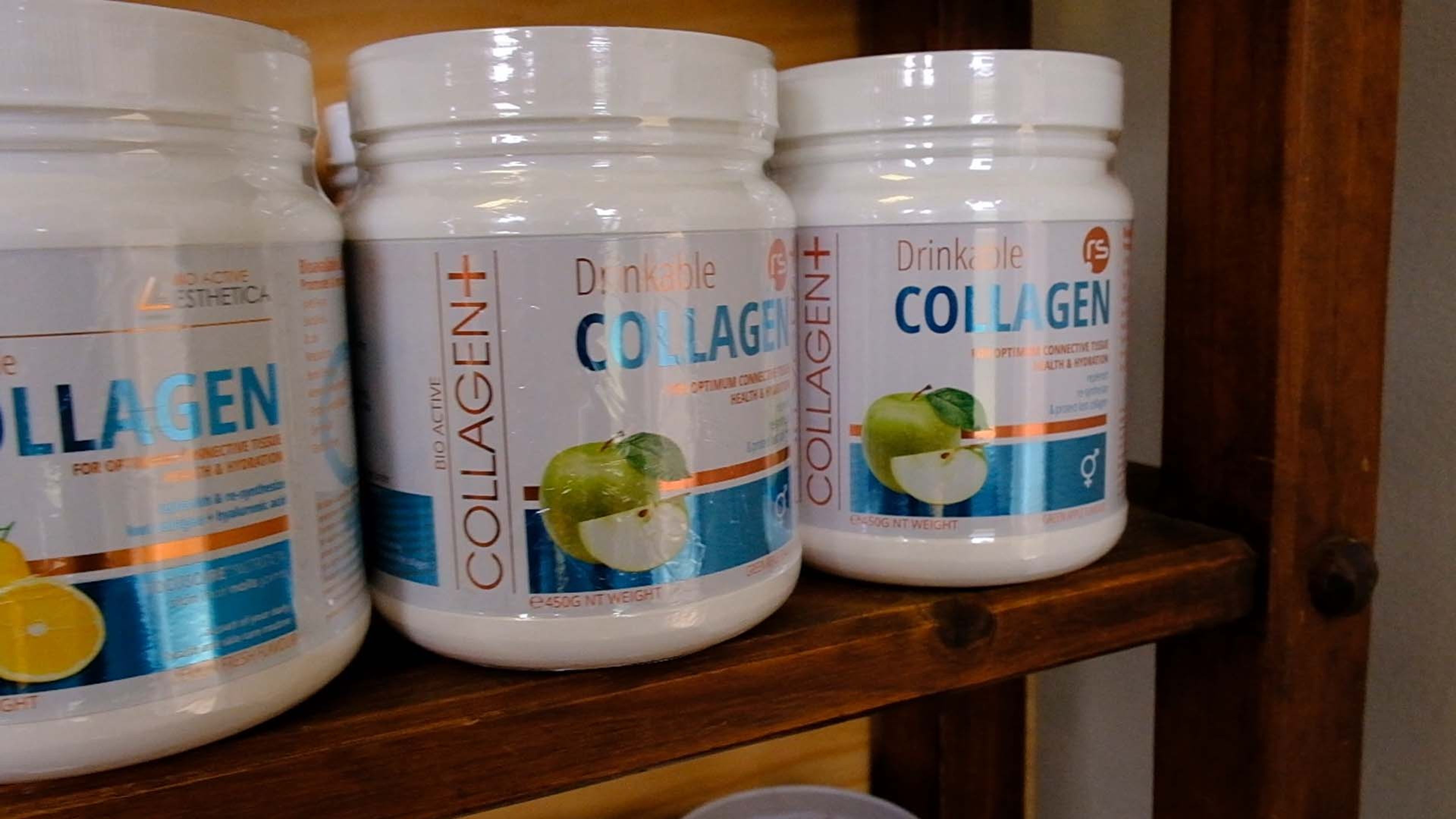 Tubs of collagen supplement on a wooden shelf