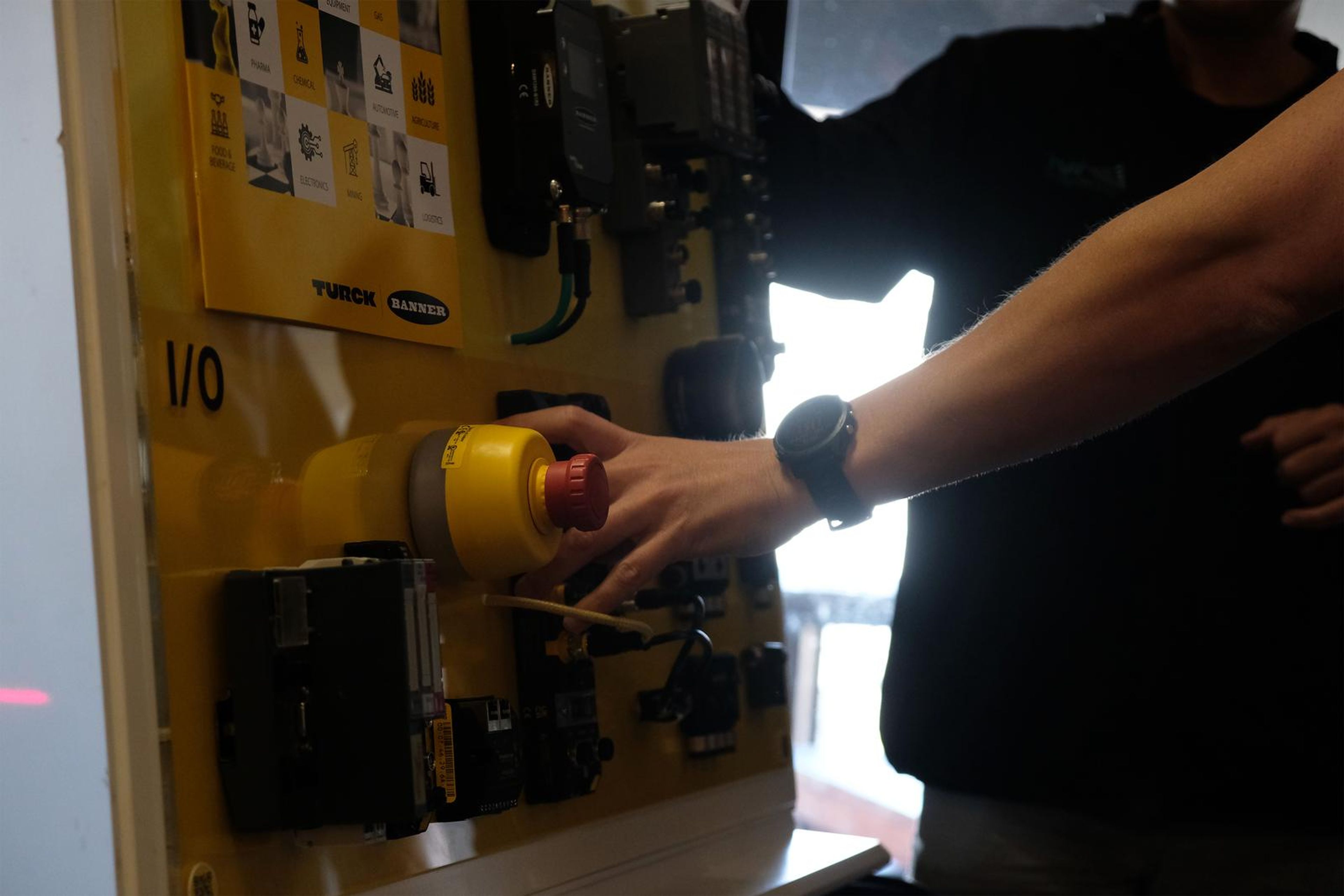 Hand pressing the emergency stop on a Turck panel