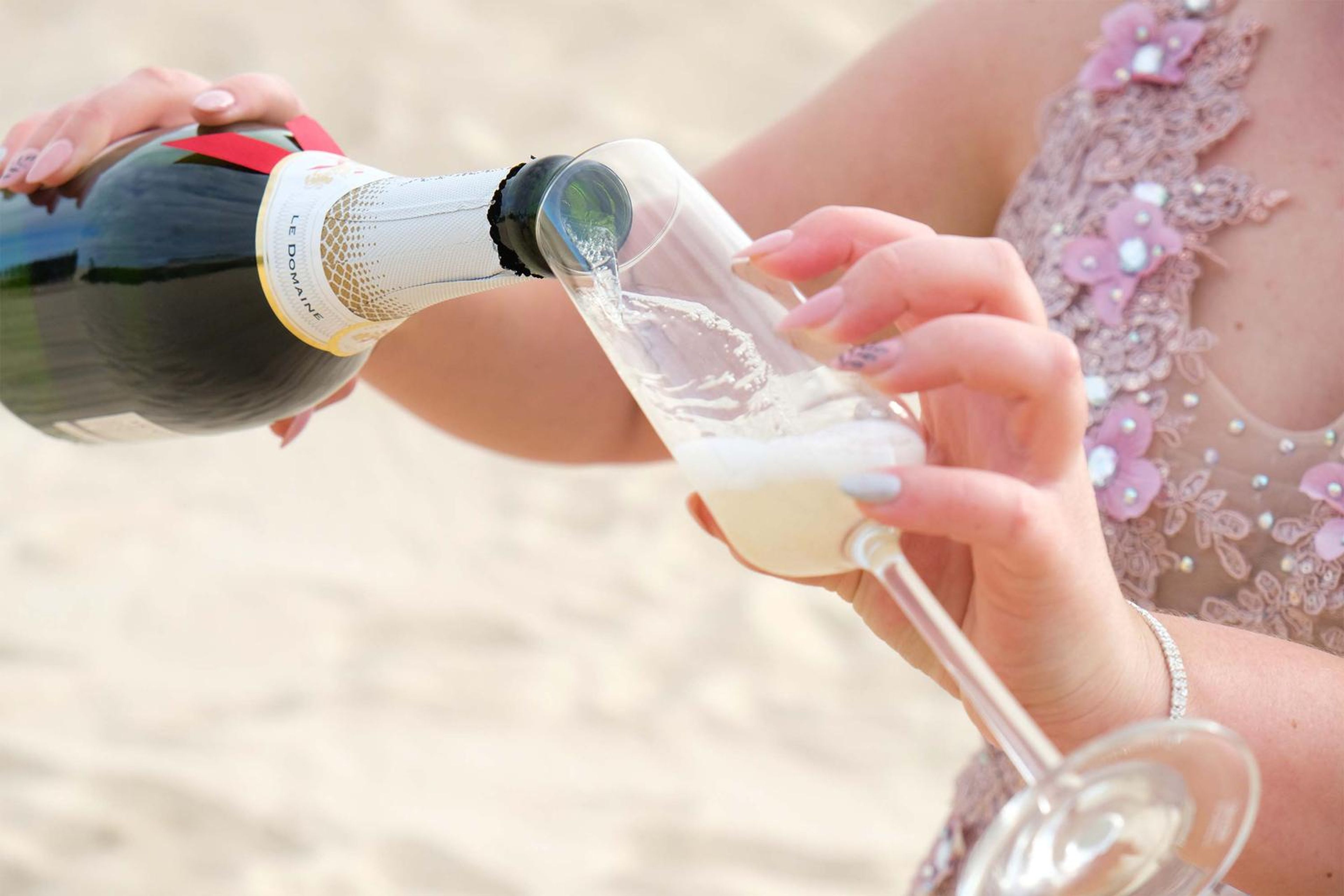 Champagne being poured into a glass on the sand