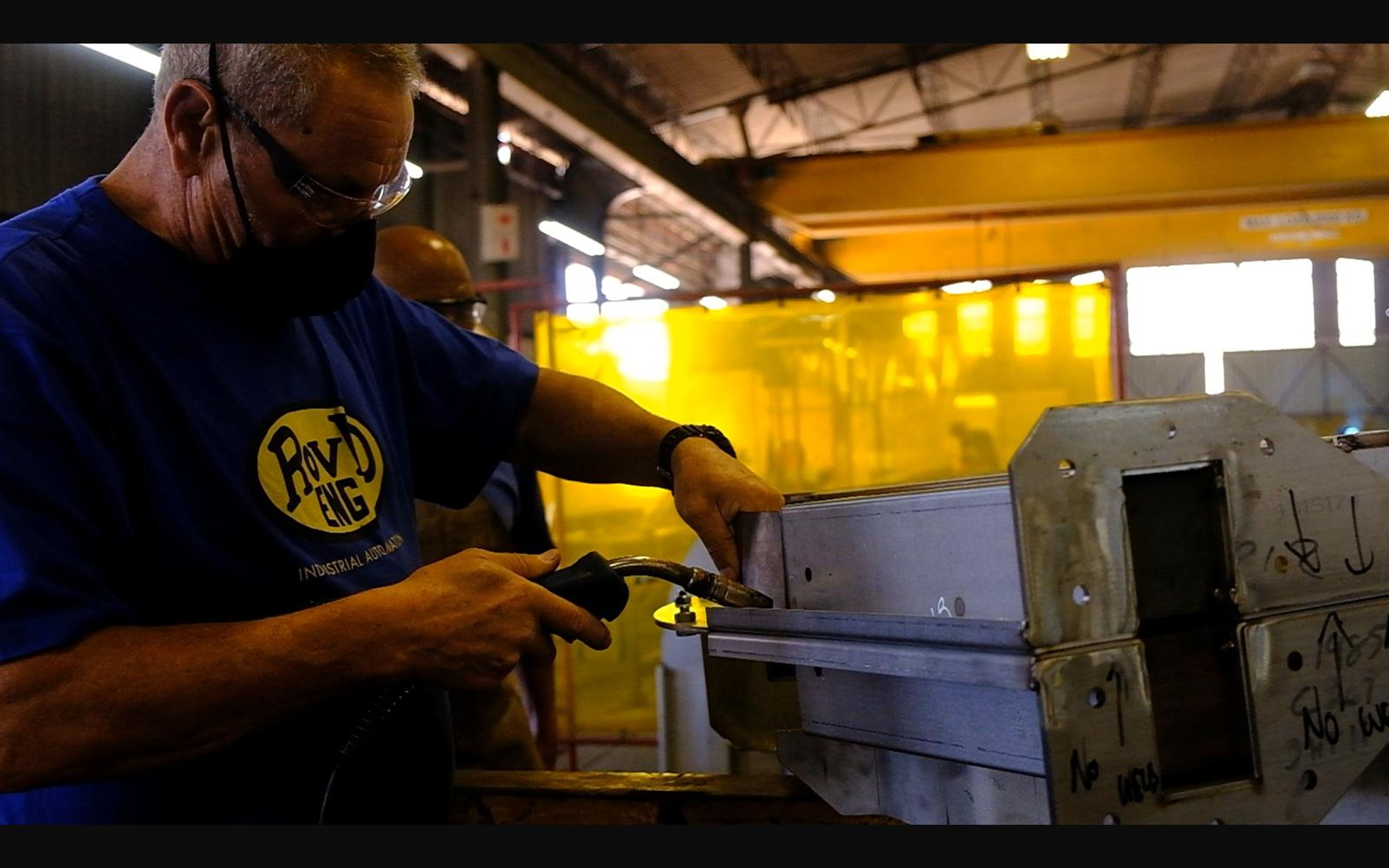 Fabricator working on a steel part in a ROVD shirt