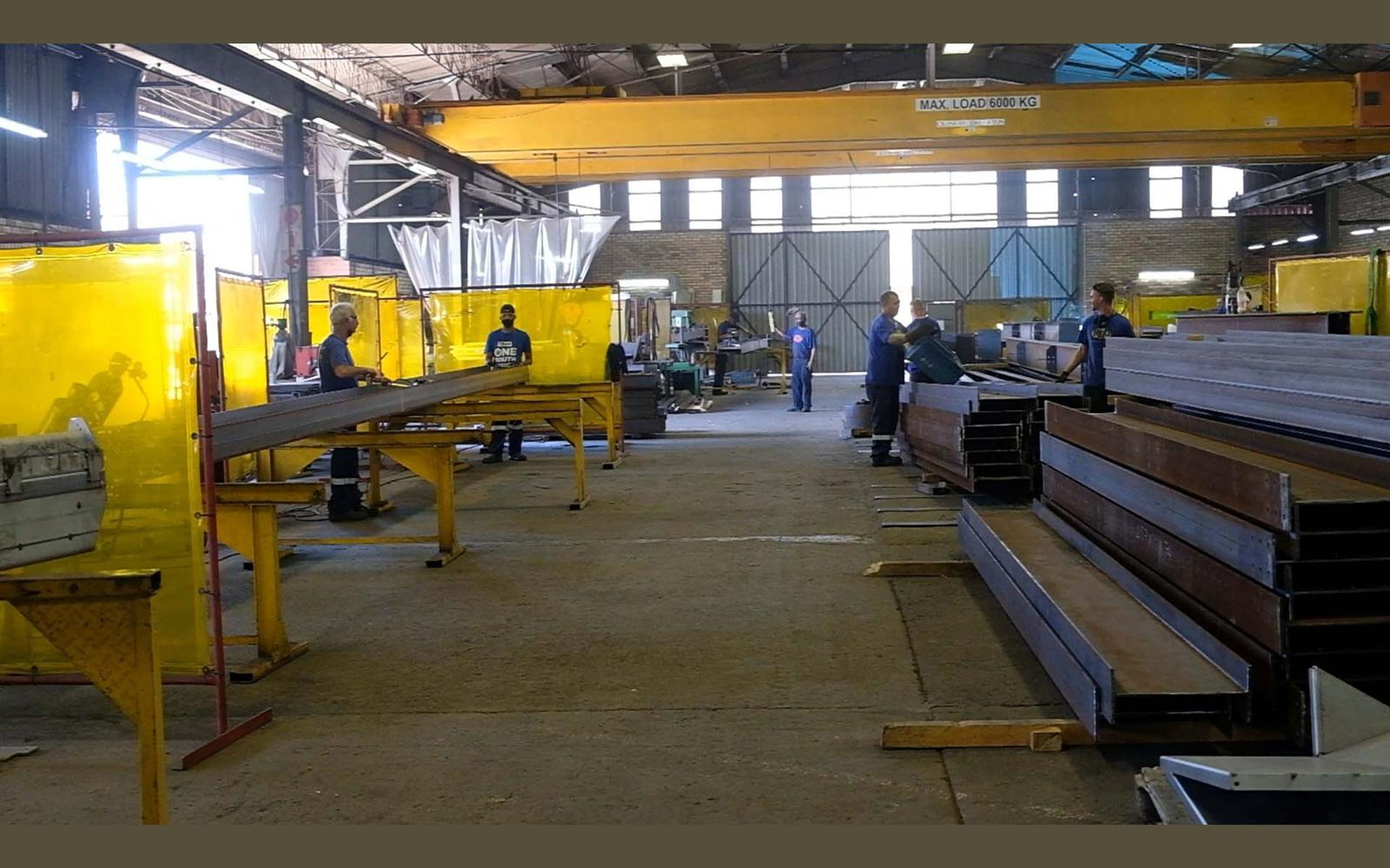 Fabrication bay with yellow welding screens and steel sections