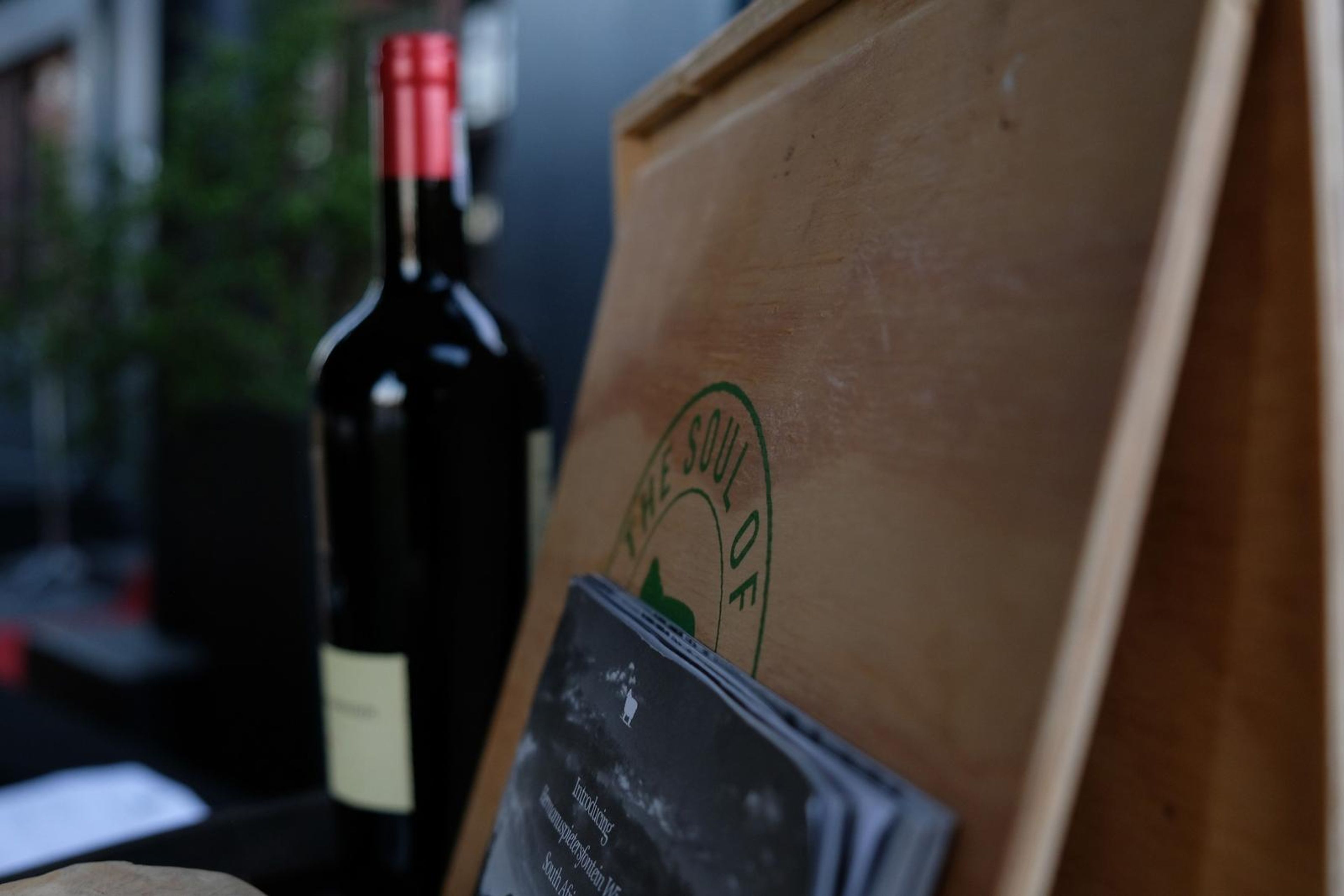 Bottle of red wine beside a wooden crate at the tasting table