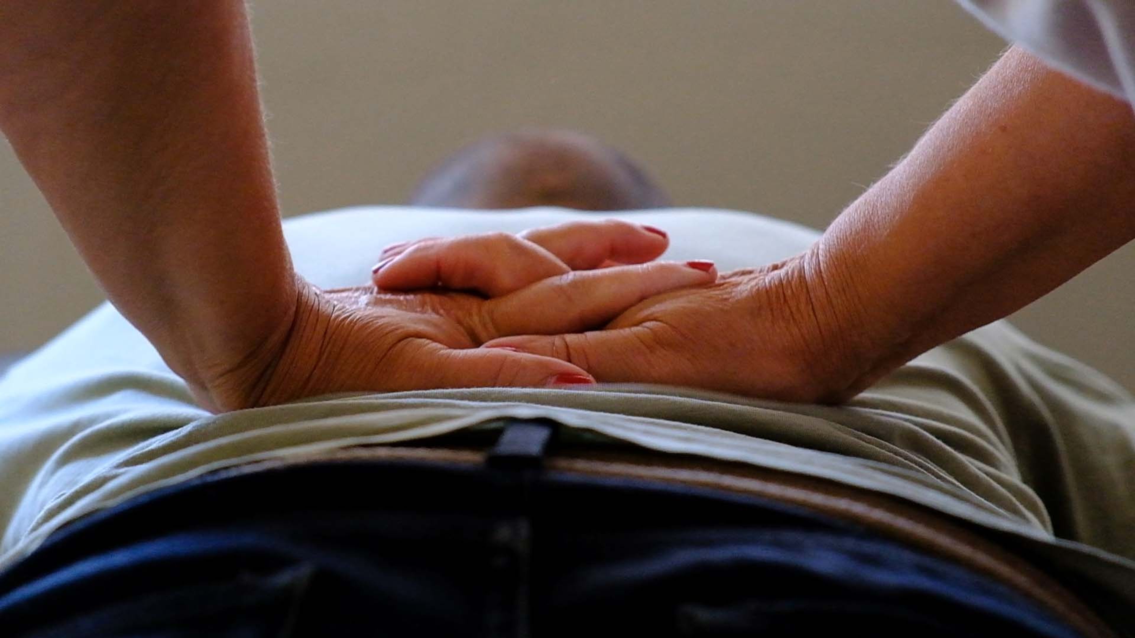 Hands resting on a client's lower abdomen during a treatment