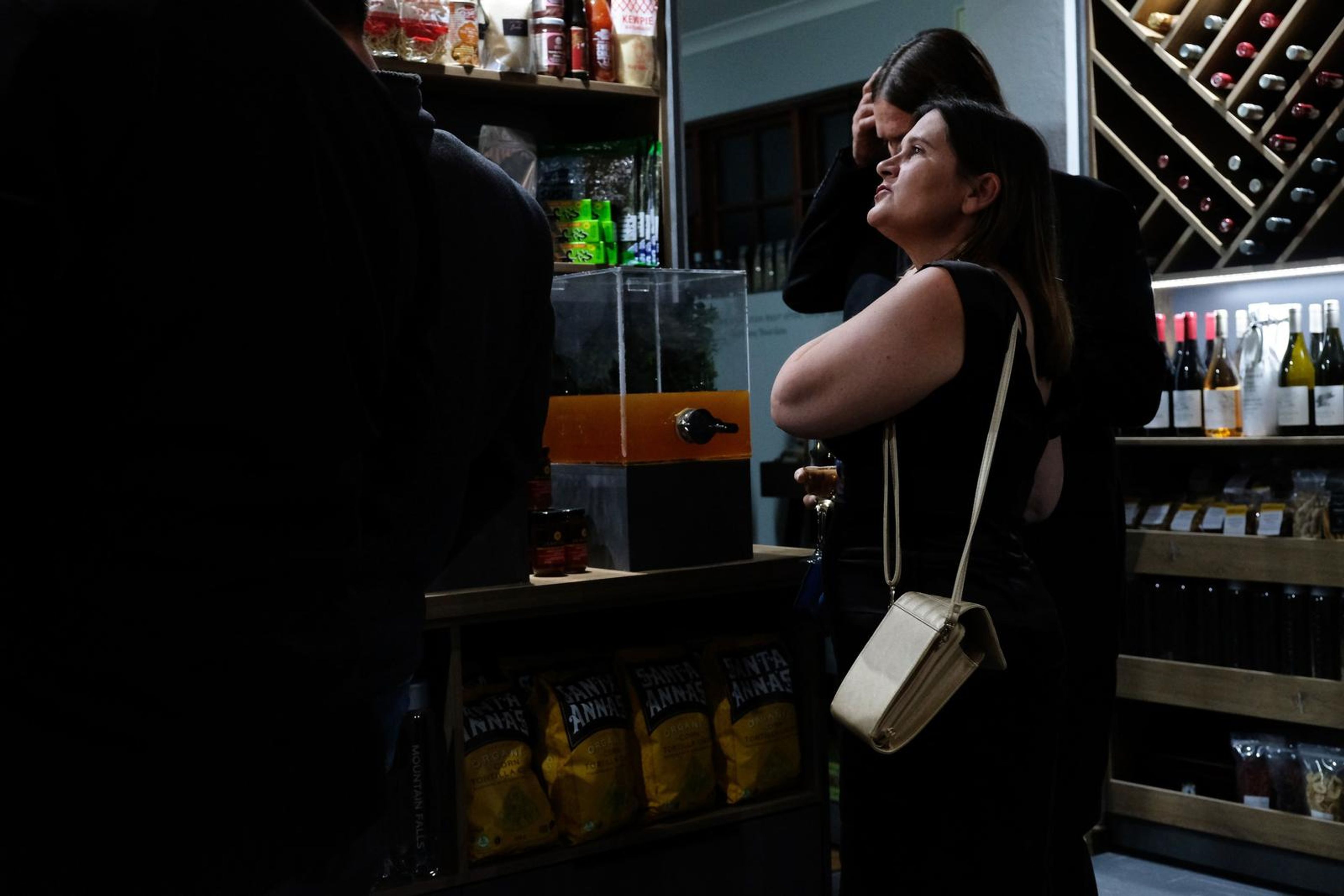 Guest in a black dress looking up at the shelves beside the wine rack