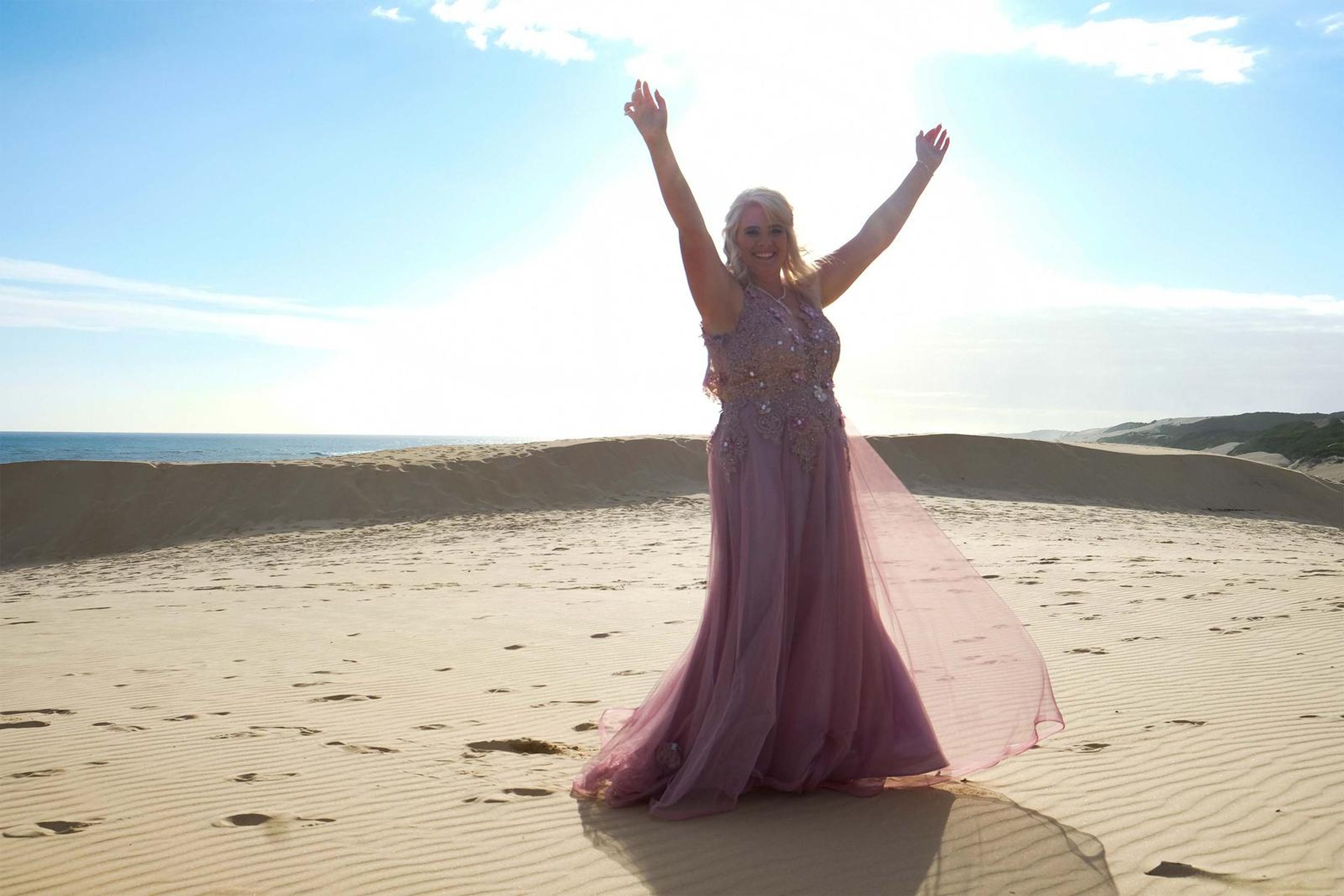 Arms raised in celebration with the sun behind