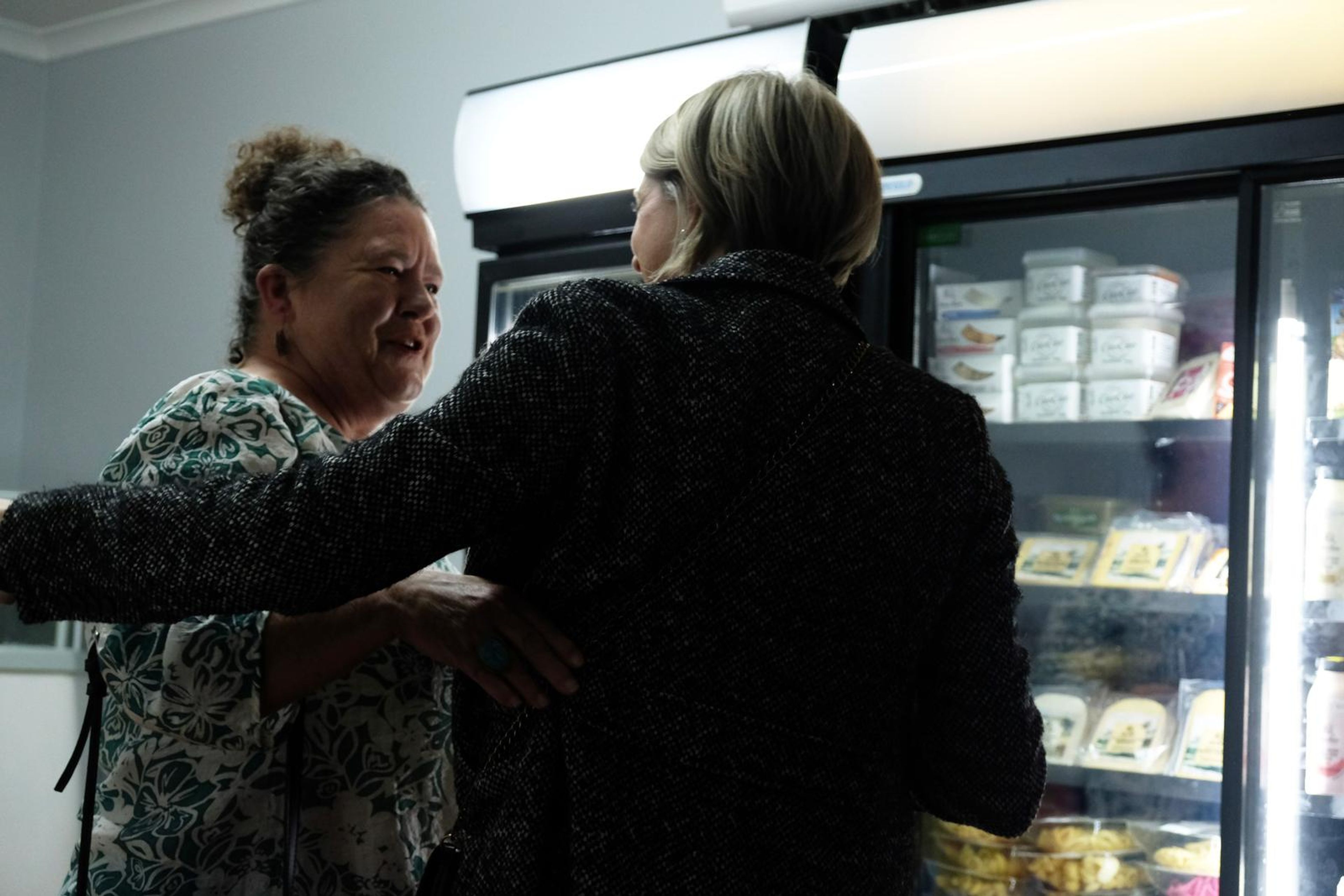 Two guests embracing in front of the fridge cabinets