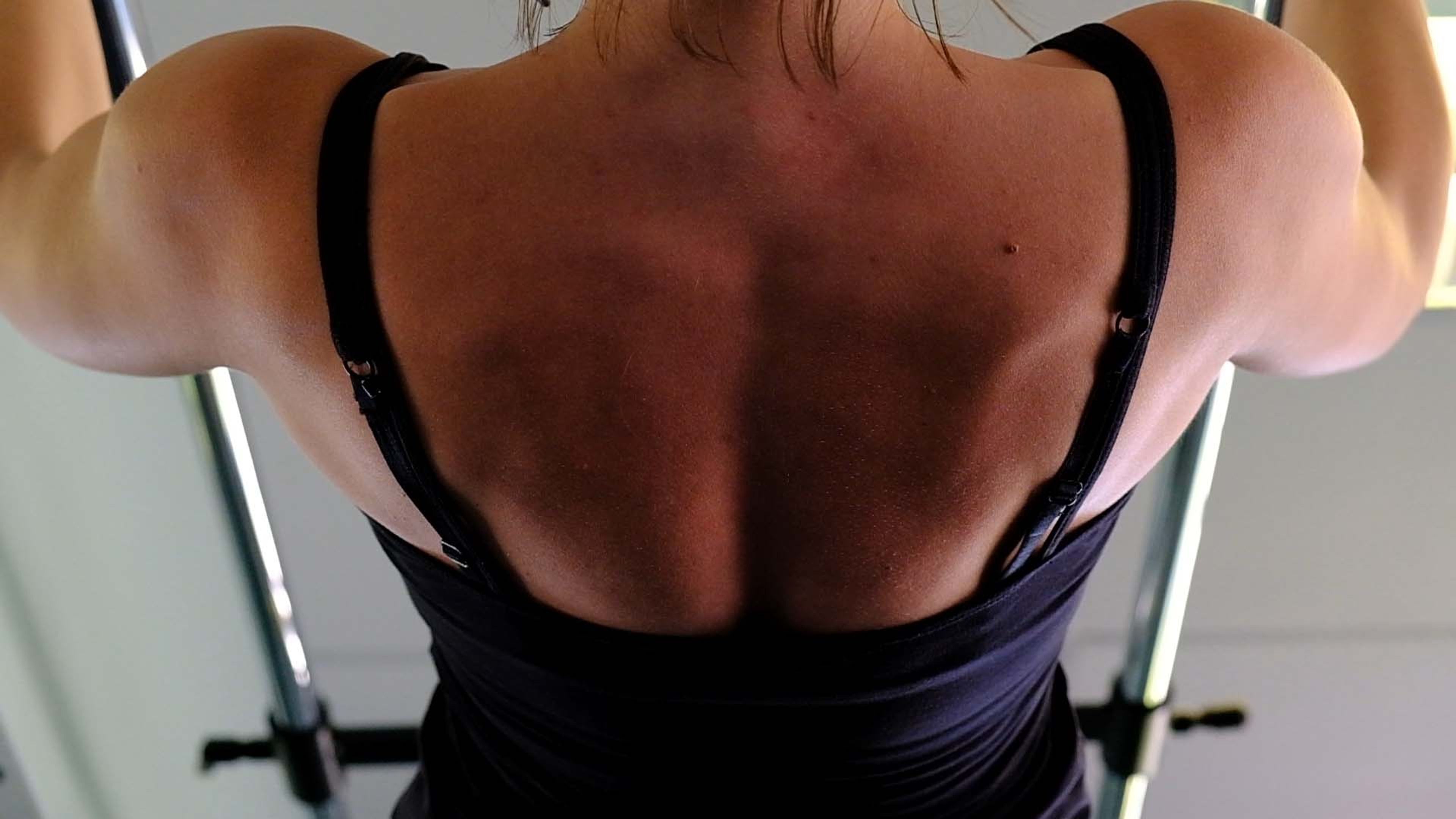Back view of a woman gripping an overhead bar