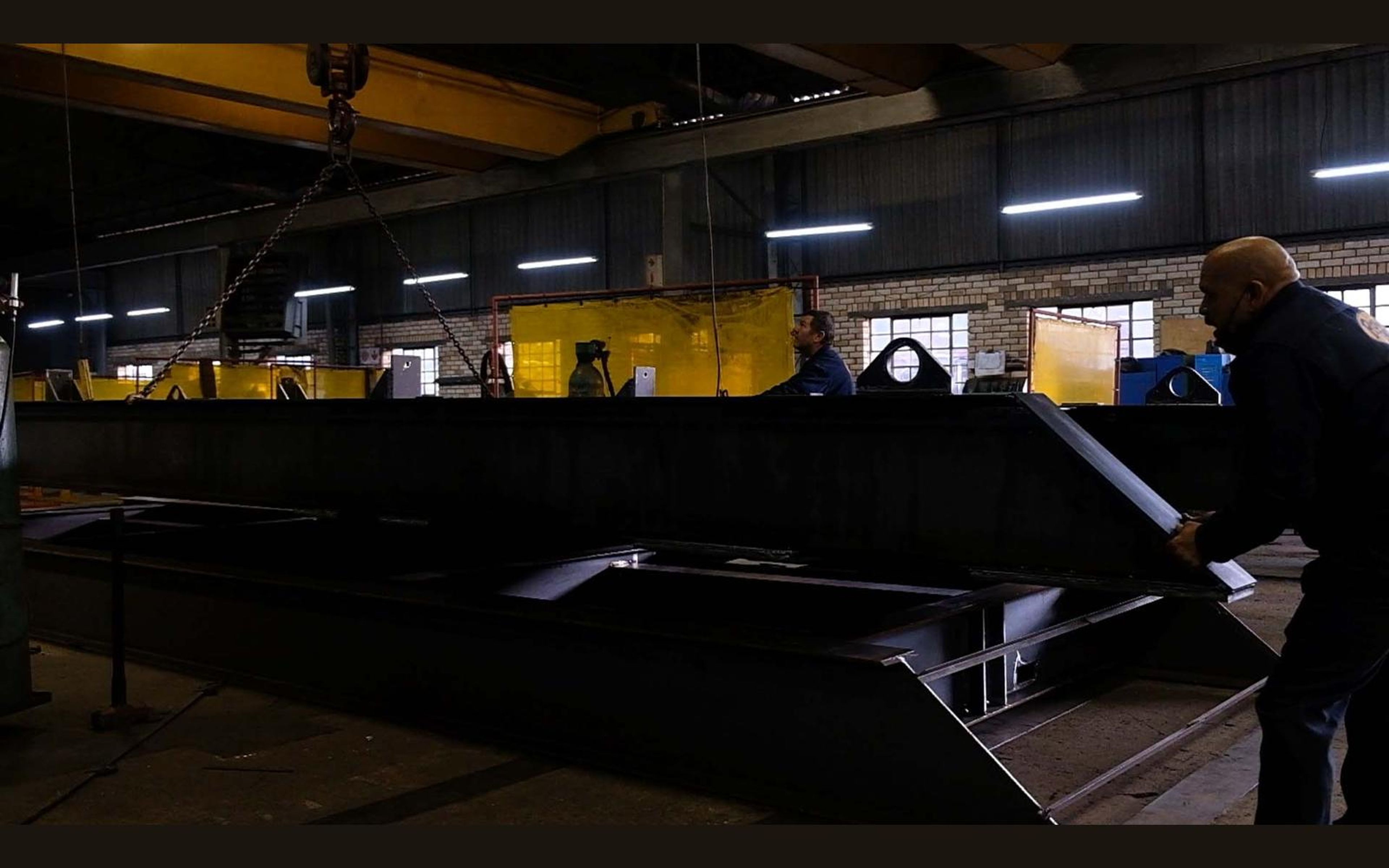 Fabrication bay with yellow welding screens and steel sections