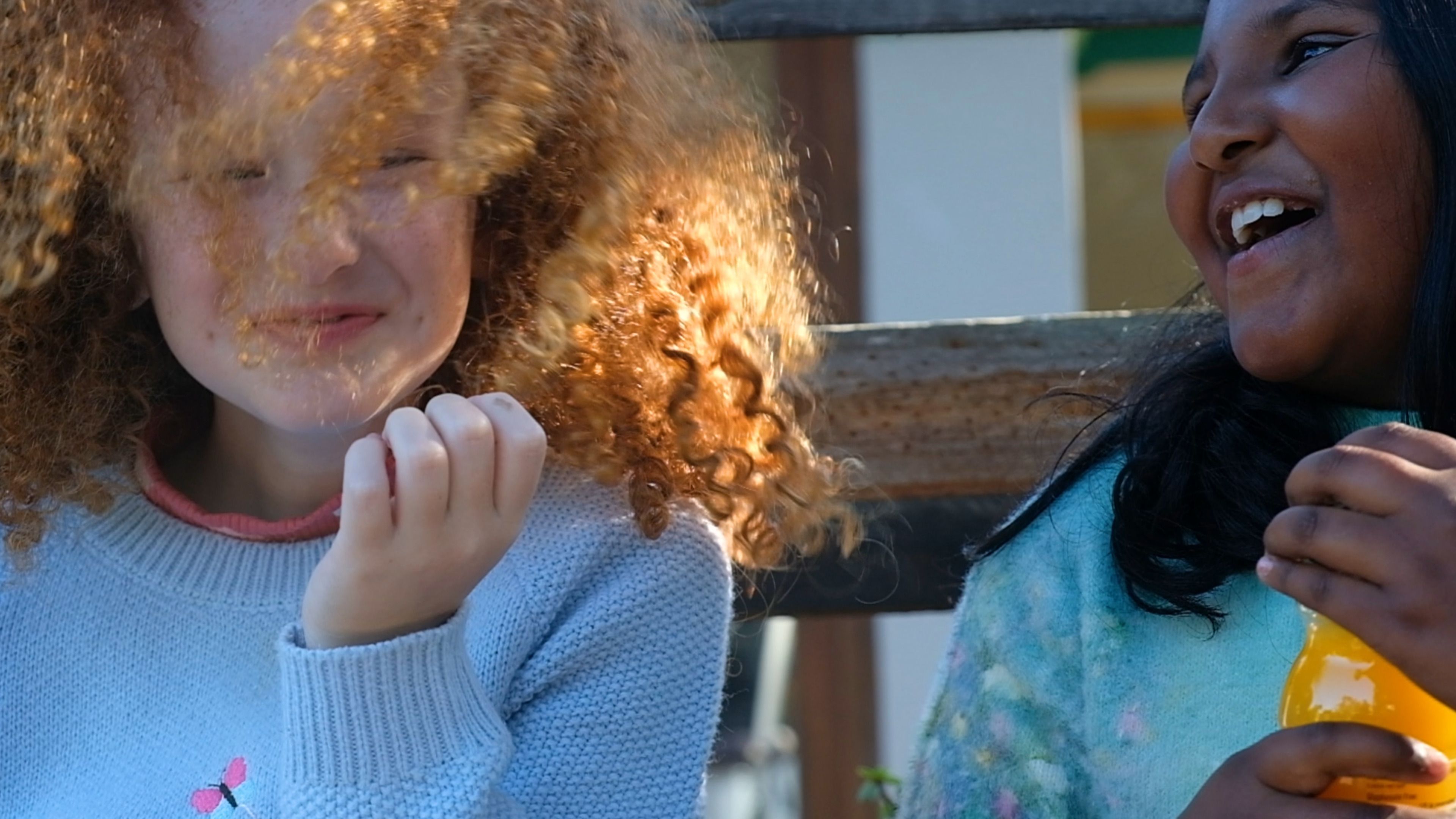 Two girls laughing together outdoors
