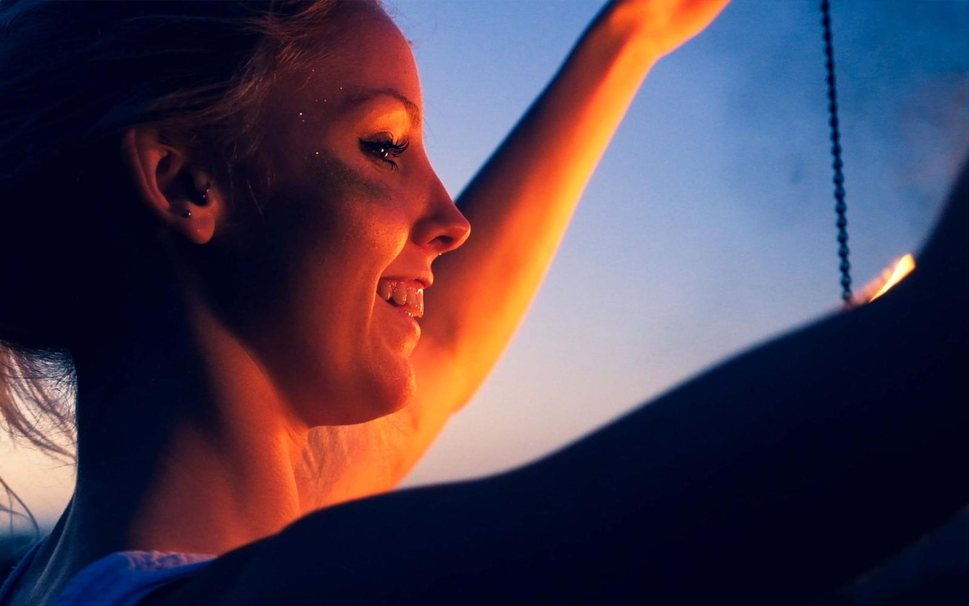 Cooler, darker version of the smiling profile close-up with deep shadows and a bright flame edge