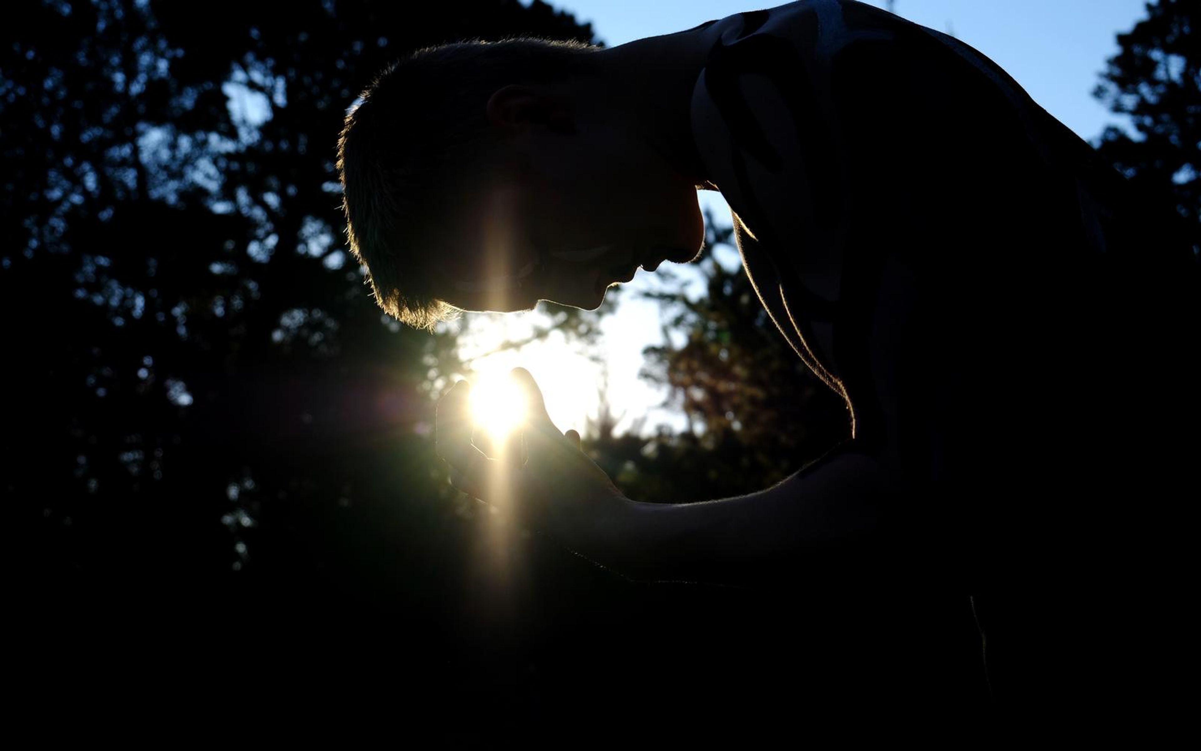 Performer bent forward in dark silhouette with a bright sun flare below his face