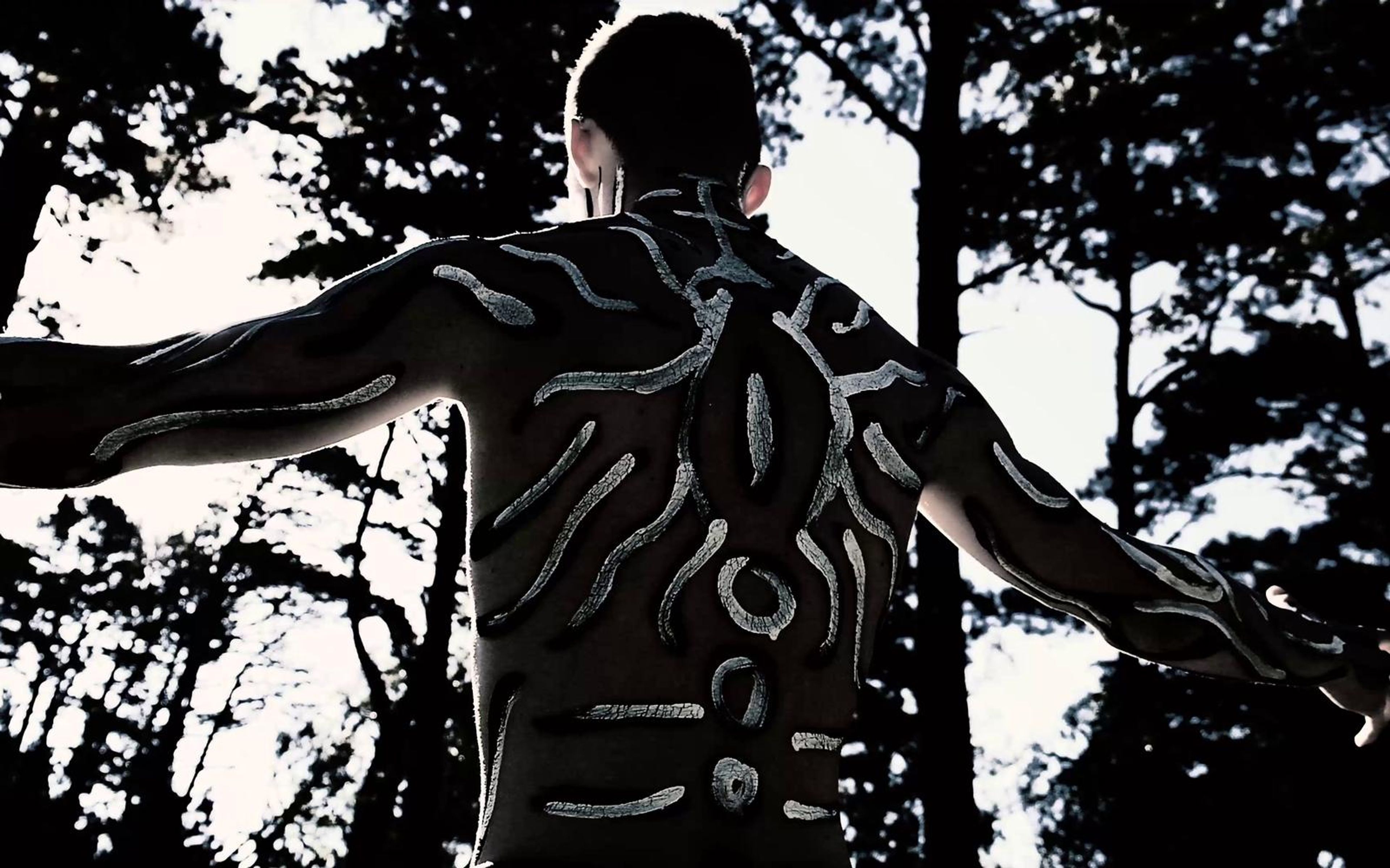 Patterned painted back with arms stretched wide among silhouetted pines